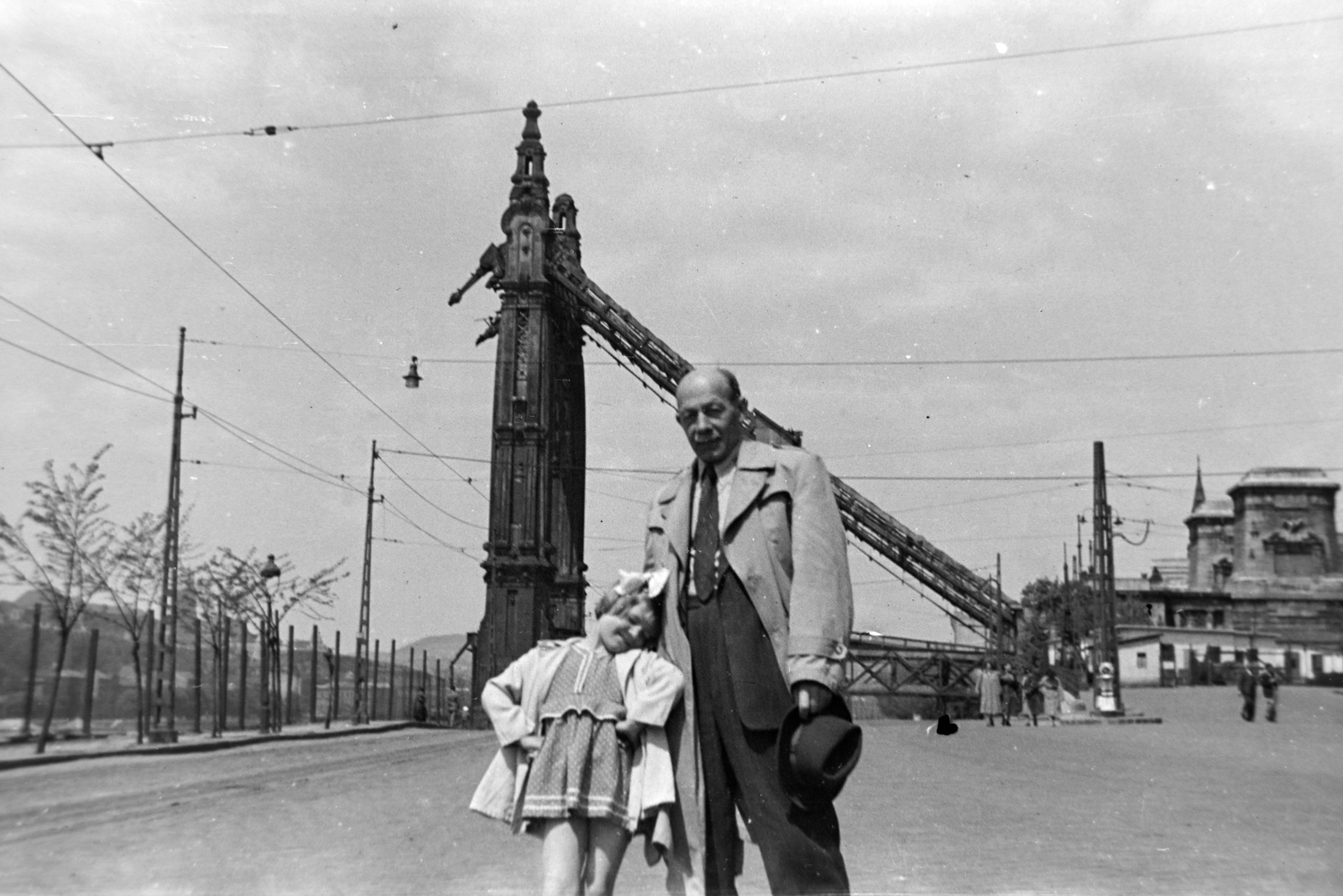 Magyarország, Budapest V., Belgrád rakpart a Március 15. tér felé nézve, szemben a lerombolt Erzsébet híd pesti hídfője., 1955, Fortepan/Album038, Budapest, kislány, masni, póz, hídroncs, kalap kézben, nagyszülő, Fortepan #186830