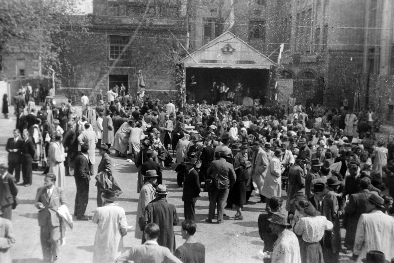 Magyarország, Budapest XIV., Thököly út 48-54., Felső Kereskedelmi Iskola (később Petrik Lajos Két Tanítási Nyelvű Vegyipari, Környezetvédelmi és Informatikai Szakgimnázium) udvara., 1946, Fortepan/Album038, Budapest, öltöny, közönség, férfiak, kabát, nők, kalap, ballonkabát, bámészkodás, pódium, Fortepan #186862