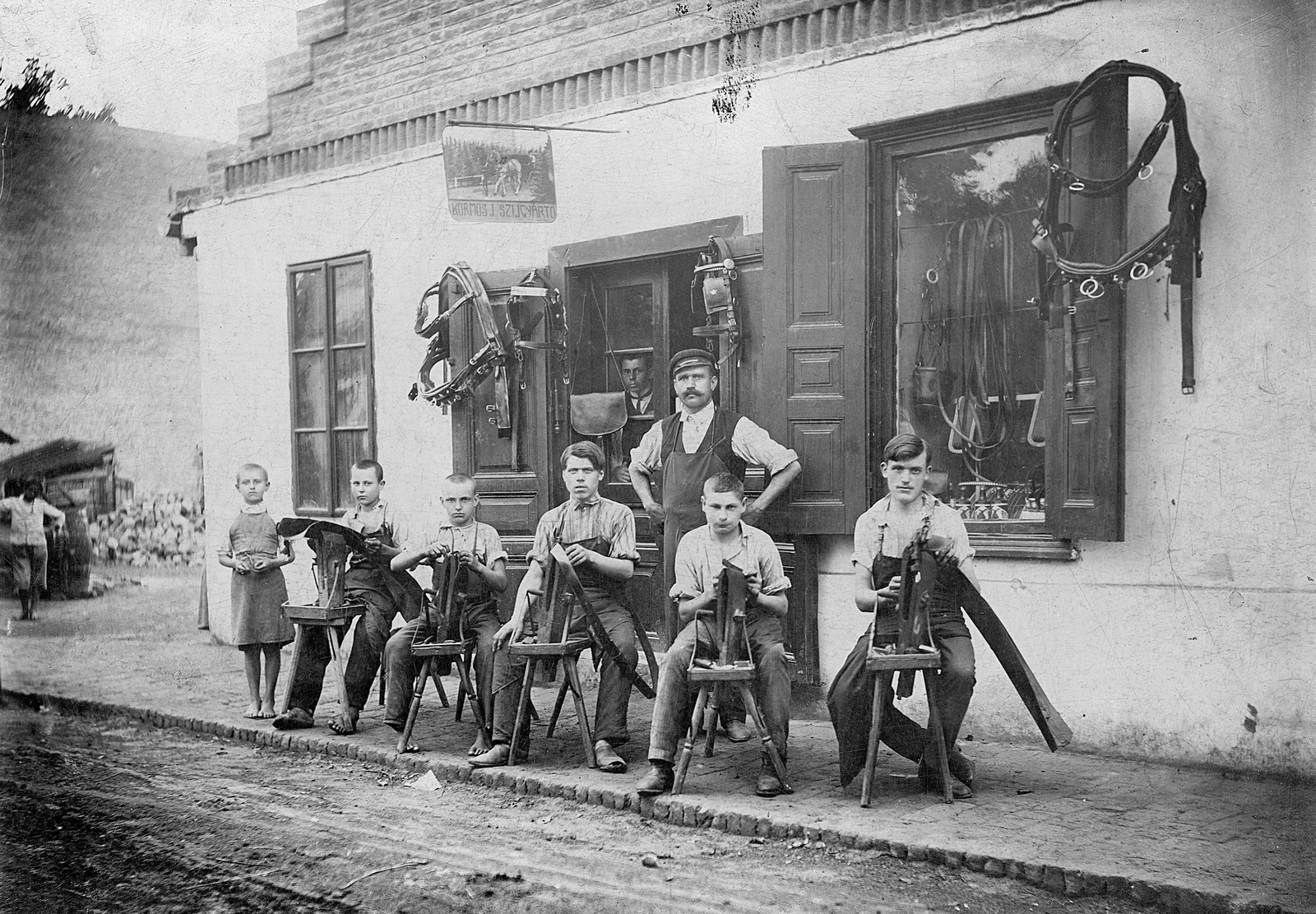 Magyarország, Dombóvár, Petőfi utca, Kormos szíjártó mester műhelye., 1908, Erky-Nagy Tibor, kirakat, cégtábla, műhely, kézműipar, üzletportál, szíjgyártó, lószerszám, inas, kihalt mesterség, Fortepan #18979