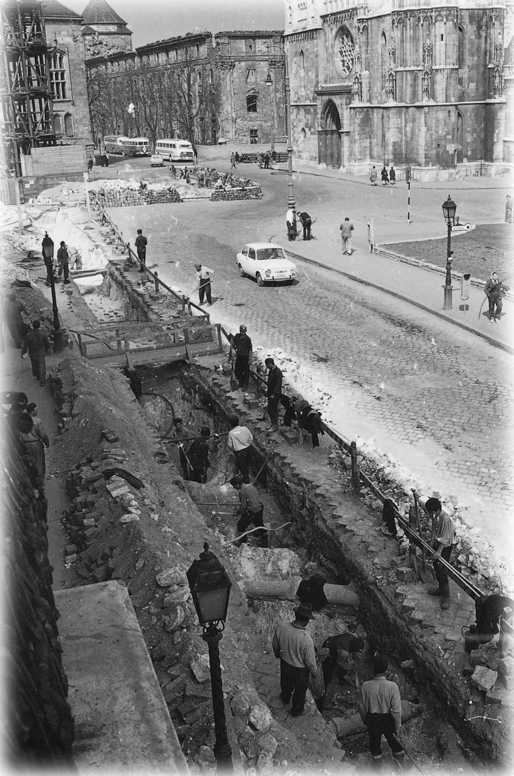 Hungary, Budapest I., Tárnok utca, távhővezeték építése. Szemben a Szentháromság téren, a felállványozott Szentháromság-szobor, jobbra a Mátyás-templom és mögötte az egykori jezsuita kollégium (később Hilton szálló) épületének részlete., 1968, FŐTÁV, Budapest, Fortepan #191264