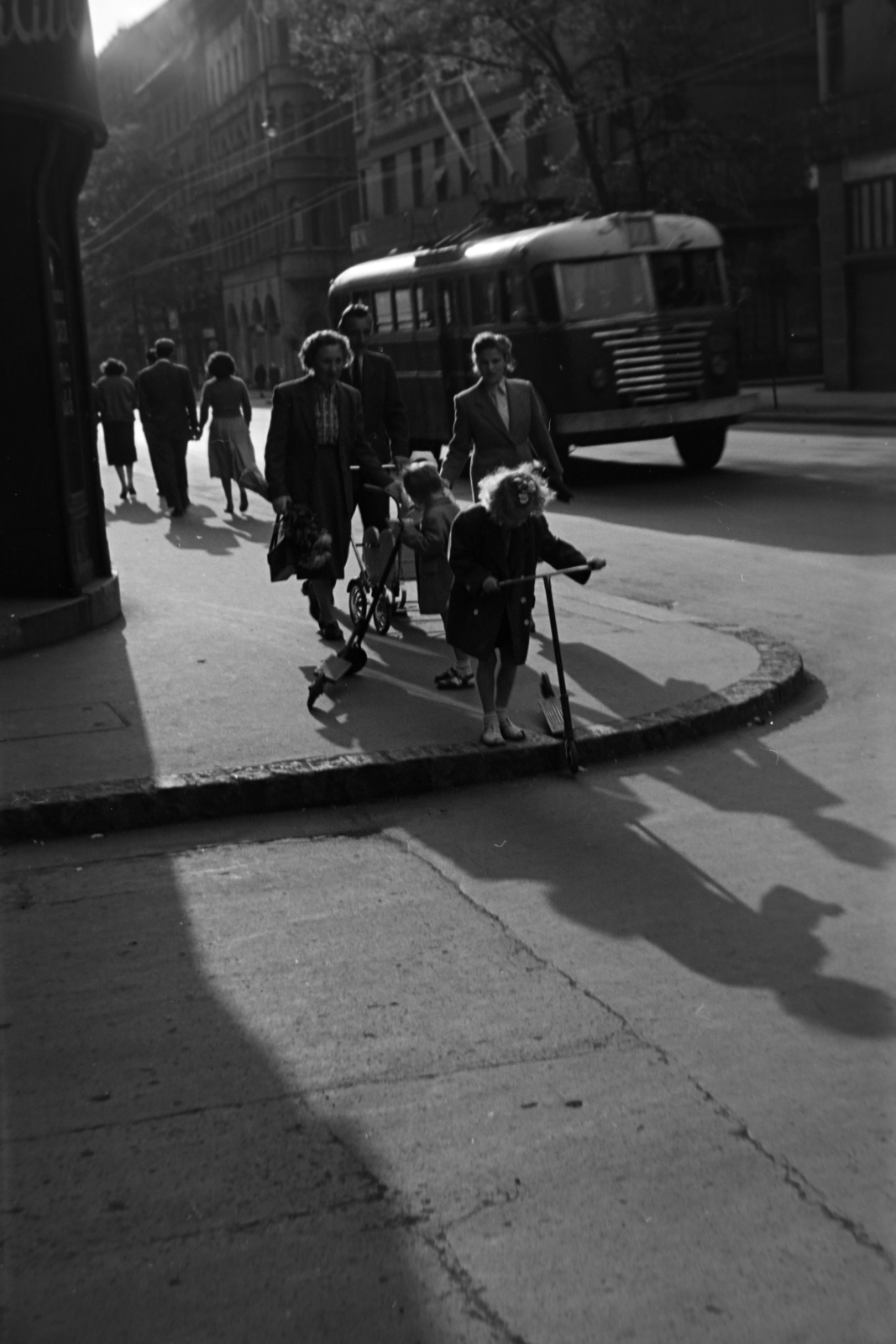 Magyarország, Budapest VIII., Baross utca, a mára megszűnt Beniczky Lajos utcánál. Szemben a trolibusz mögött a Vasas köz - Szűz utca közötti ház látszik., 1954, Kriss Géza, Budapest, gyerekek, autóbusz, árnyék, roller, járda, Fortepan #191793