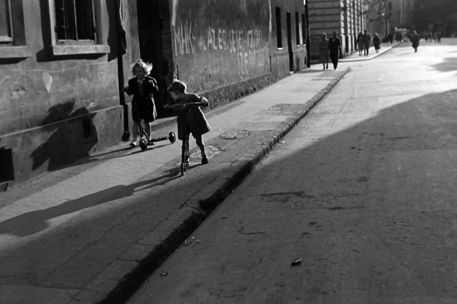 Hungary, Budapest VIII., Kis Stáció utca a Harminckettesek tere felé nézve, balra a Kisfaludy utca torkolata., 1954, Kriss Géza, Budapest, kids, scooter, graffiti, pavement, Fortepan #191807