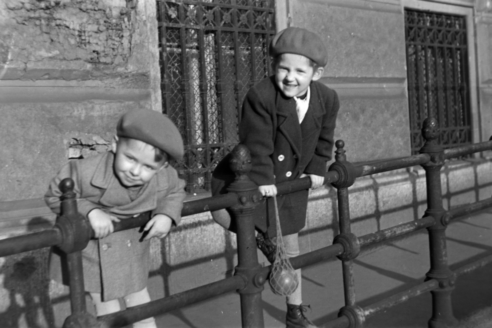Magyarország, Budapest V., lejáró az ELTE Bölcsészkar (egykor és ma Piarista Gimnázium és Rendház) épülete előtt a Szabad sajtó út feől Március 15. térre., 1955, Kriss Géza, Budapest, korlát, kisfiú, kabát, labda, svájcisapka, ablakrács, Fortepan #191819