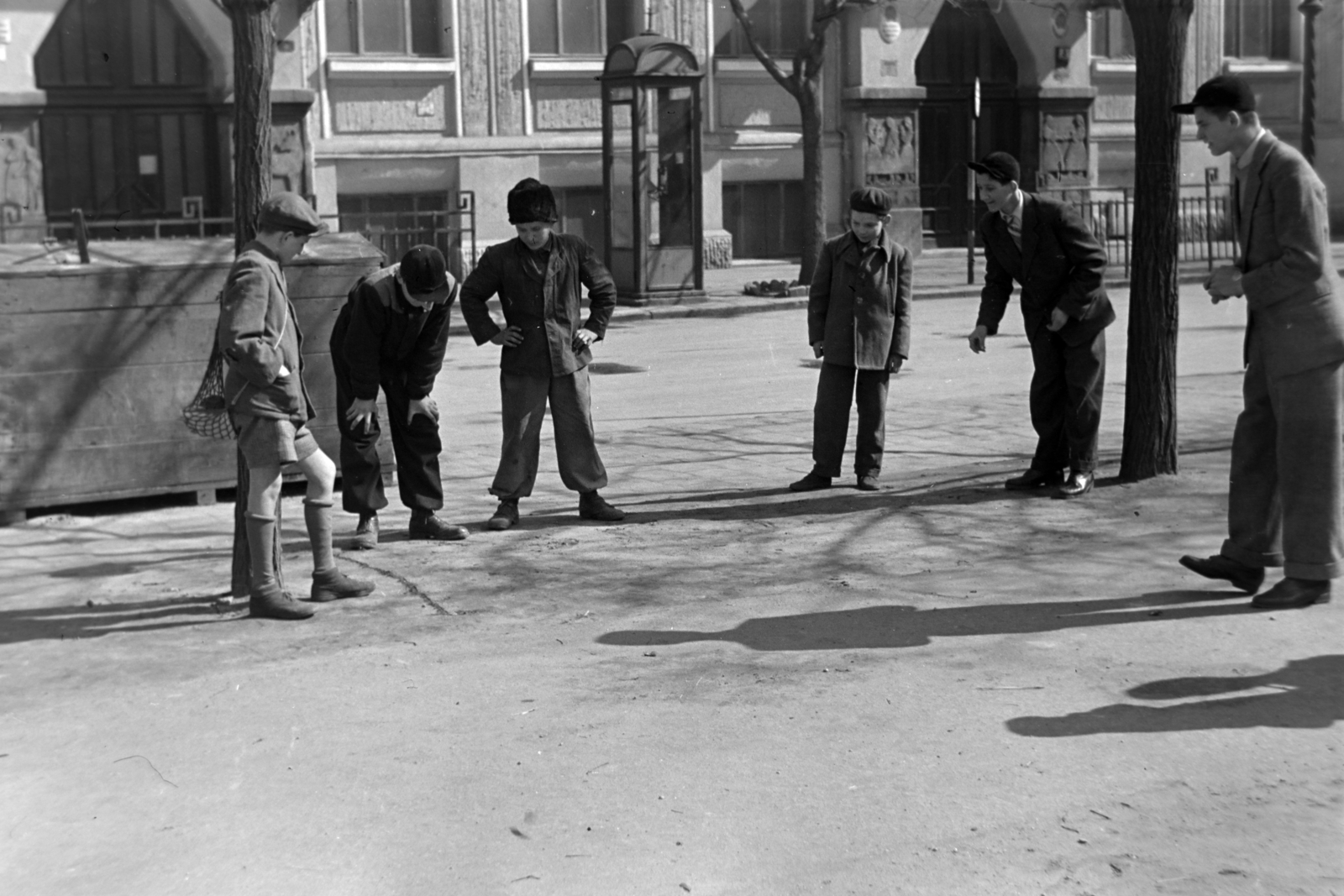 Magyarország, Budapest VIII., Horváth Mihály tér, snúrozó fiúk. Háttérben a Horváth Mihály téri Gyakorló Általános Iskola (később Budapesti Fazekas Mihály Gyakorló Általános Iskola és Gimnázium)., 1955, Kriss Géza, Budapest, telefonfülke, játék, fiúk, fény-árnyék, Fortepan #191885