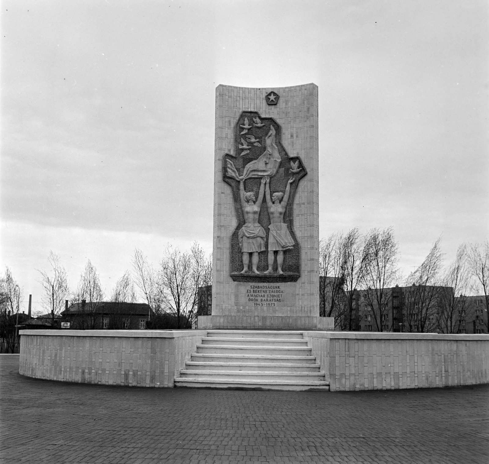 Magyarország, Budapest X., Óhegy (Szovjet-magyar barátság) park, Szovjet–magyar barátság emlékmű. Búza Barna szobrászművész pirogránit alkotása 1975-ben került felavatásra, Kisfaludi Strobl Zsigmond eszmei tervei alapján. Háttérben a Dér utca (Komszomol sétány) házsora., 1975, Bojár Sándor, Budapest, Kisfaludi Strobl Zsigmond-terv, Fortepan #195177