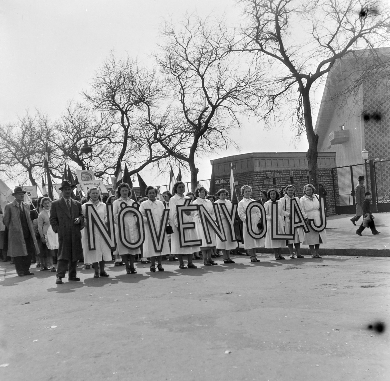 Hungary, Népstadion, Budapest XIV., Stefánia (Vorosilov) út, május 1-i felvonulás résztvevői. Háttérben a Népstadion., 1955, Keveházi János, Budapest, label, overall, women, photo aspect ratio: square, hold in arms, Fortepan #197263