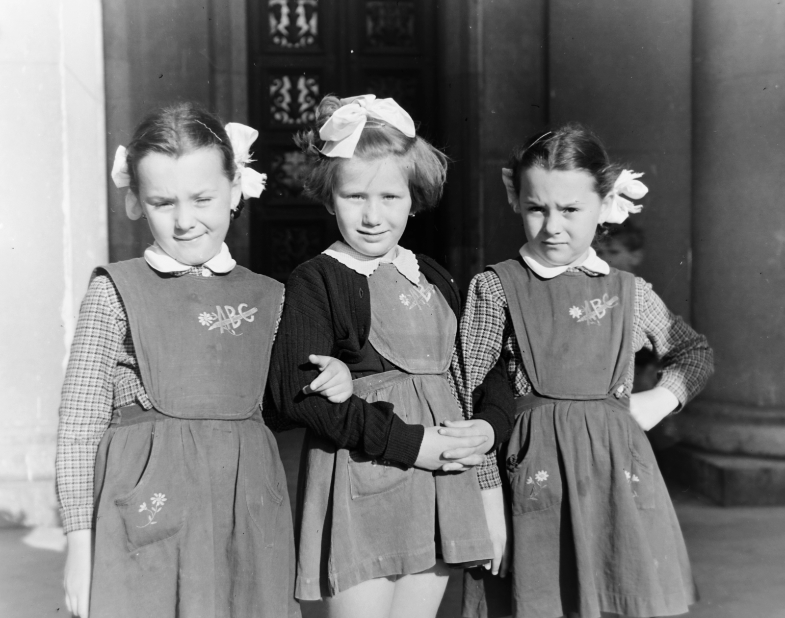 Magyarország, Budapest VIII., Magyarok Nagyasszonya (Rezső) tér, a felvétel a Magyarok Nagyasszonya-templom kapujában készült., 1957, Keveházi János, Budapest, lányok, csípőre tett kéz, masni, kötényruha, Fortepan #197503