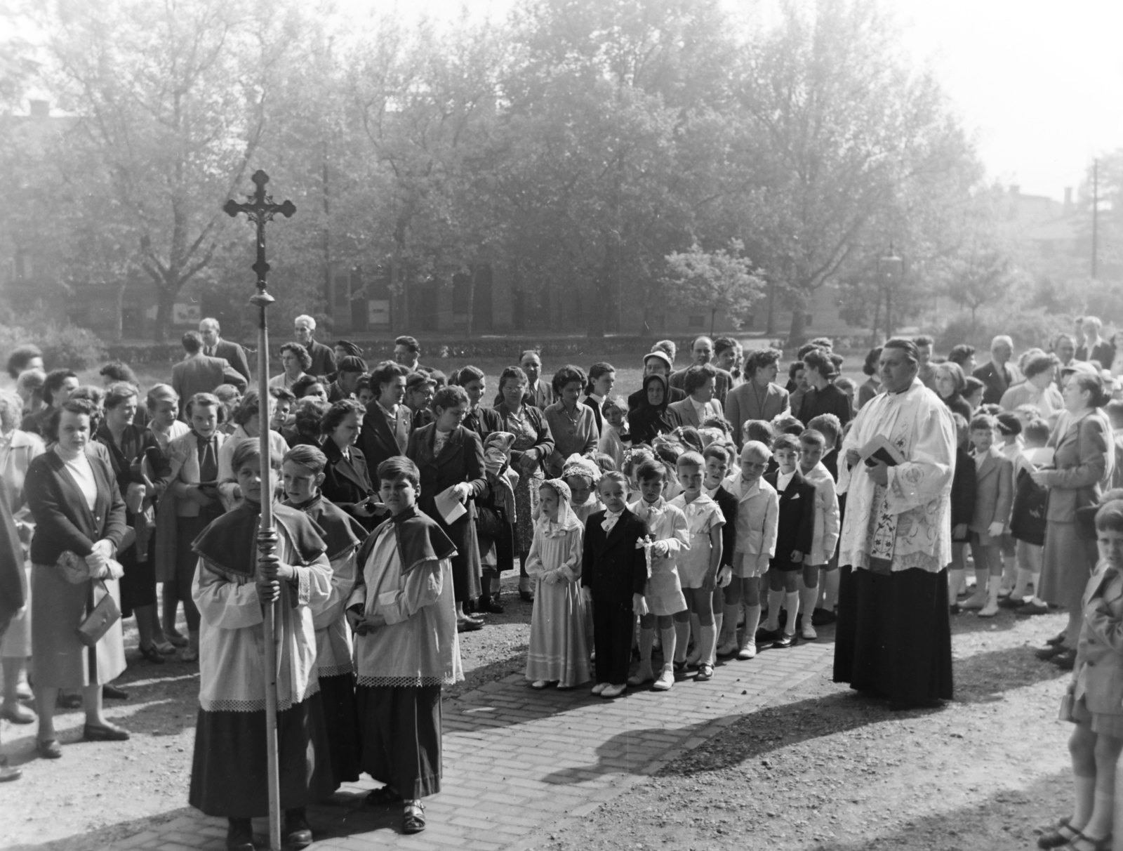 Magyarország, Budapest VIII., Magyarok Nagyasszonya (Rezső) tér, elsőáldozók a Magyarok Nagyasszonya-templom mellett., 1957, Keveházi János, Budapest, pap, gyerekek, feszület, karing, Fortepan #197508