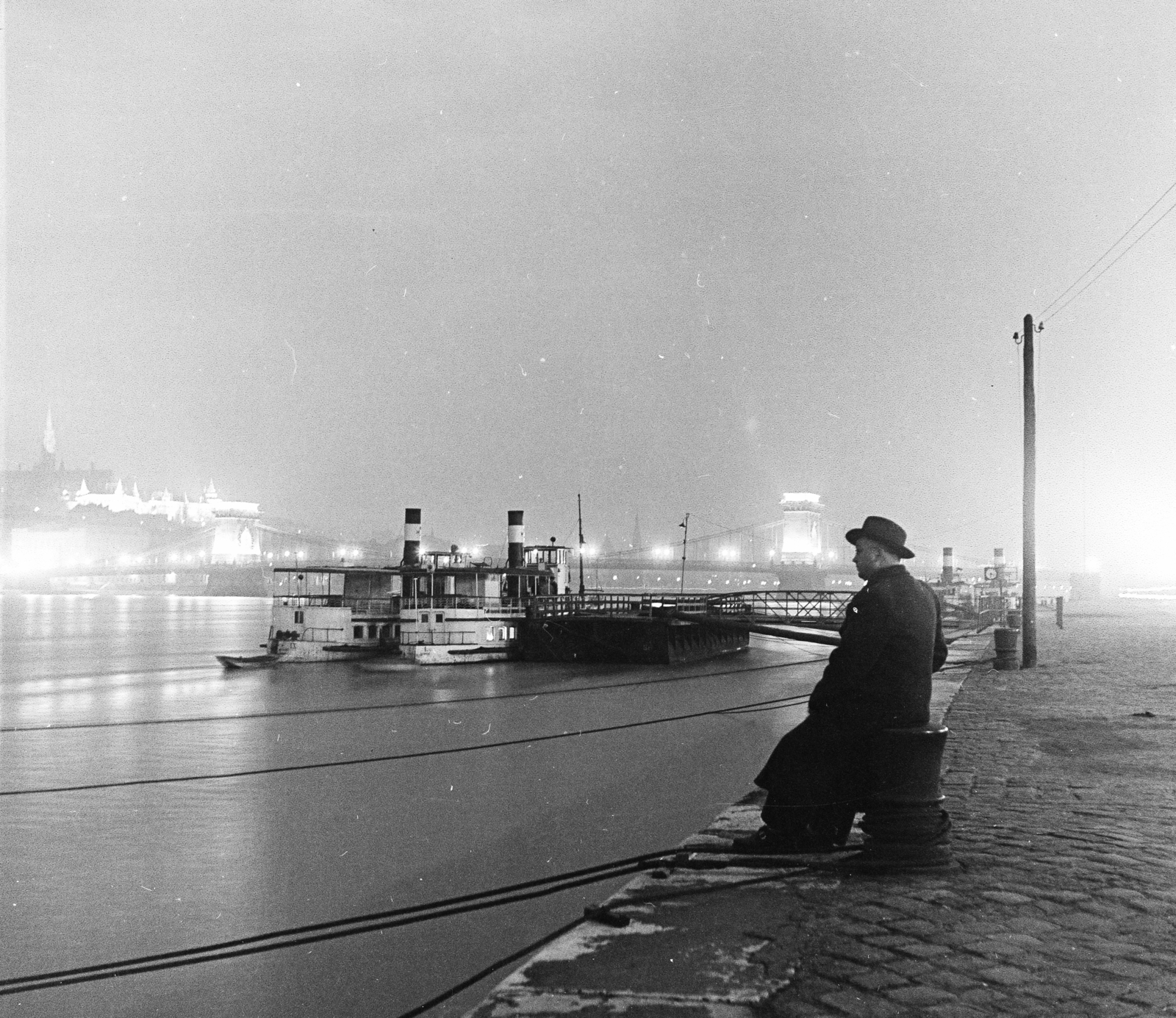 Hungary, Budapest V., pesti alsó rakpart, háttérben a kivilágított Széchenyi Lánchíd és Halászbástya., 1958, Keveházi János, Budapest, hat, coat, mooring bollard, night, Fortepan #197662