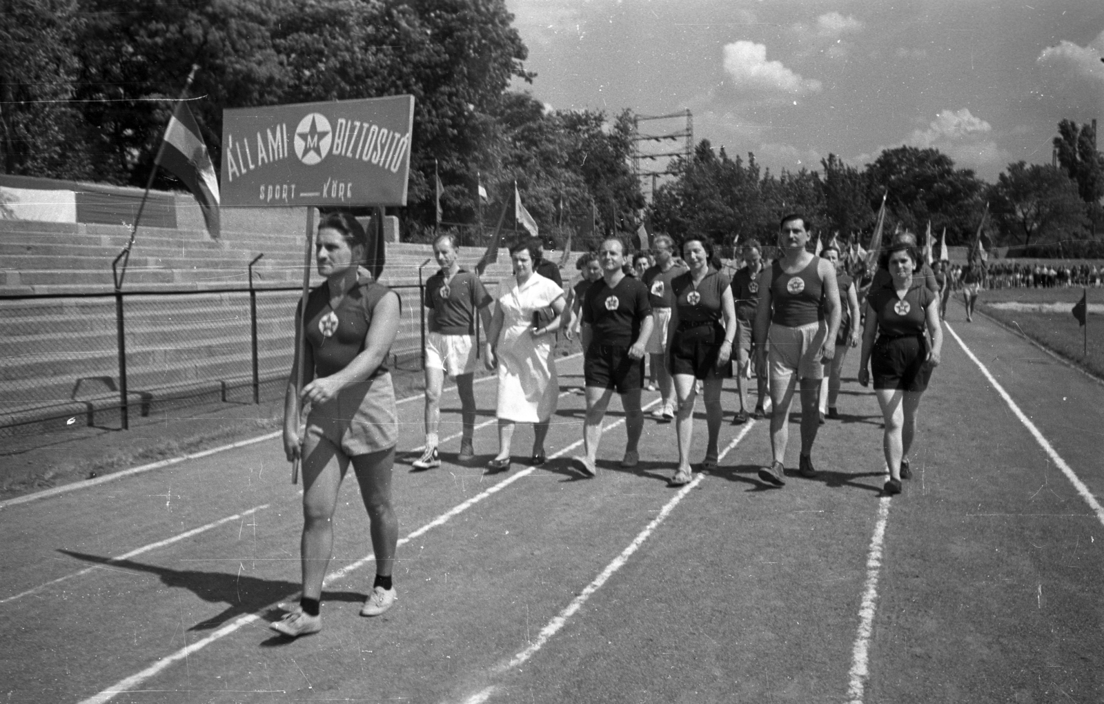 Magyarország, Népliget, Budapest X., Építők pálya., 1955, Bauer Sándor, felvonulás, sportpálya, sportoló, tábla, Állami Biztosító, Budapest, Fortepan #199529