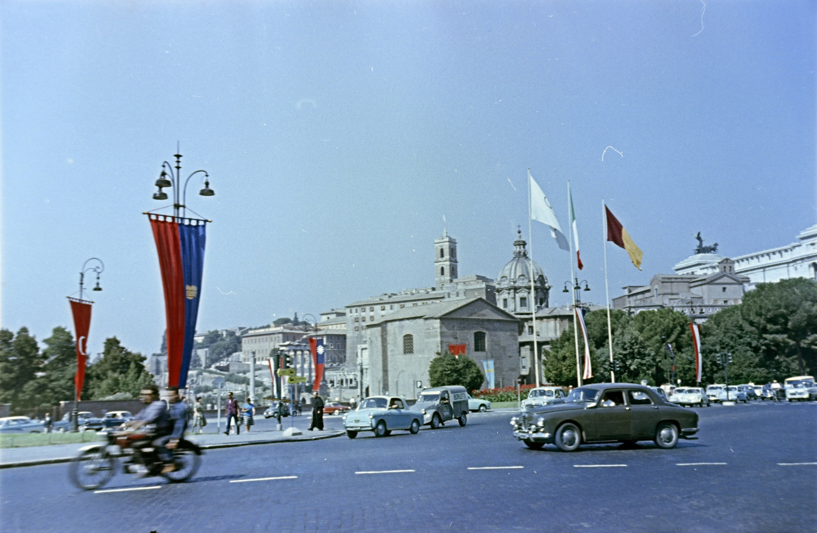 Olaszország, Róma, Via dei Fori Imperiali, a középen álló épület a Curia Iulia, mögötte a kupolás épület a Szent Lukács és Martina temploma., 1960, Gergely György, színes, zászló, motorkerékpár, automobil, Fortepan #201329