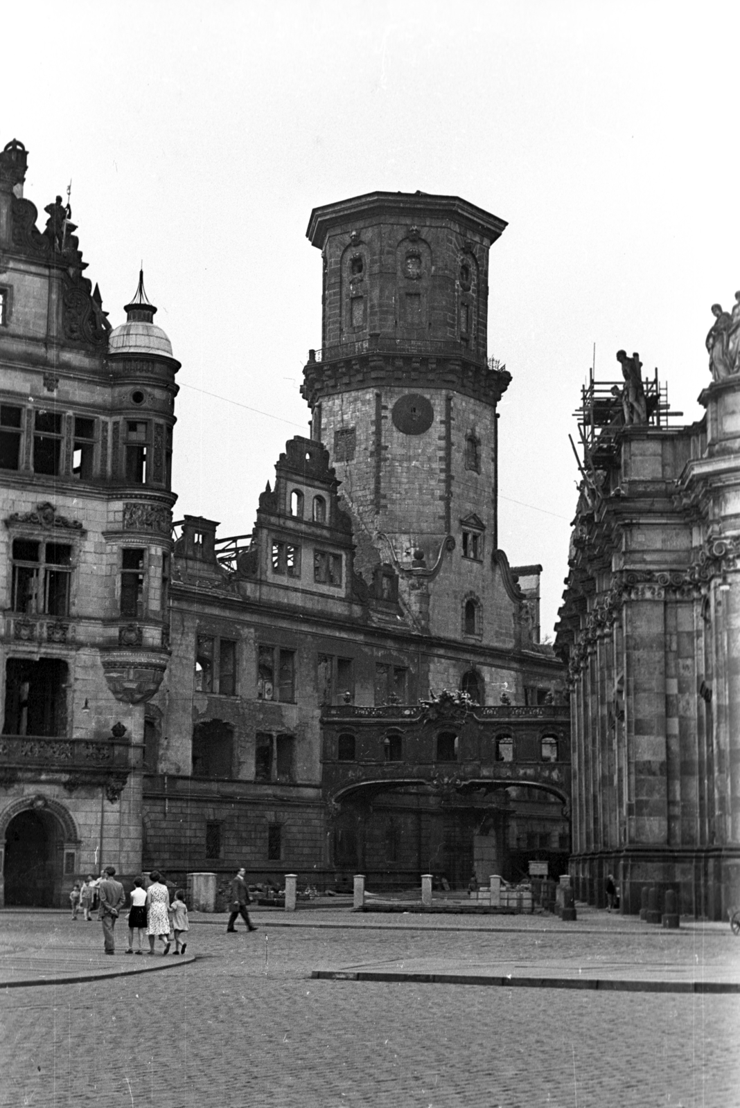 Germany, Dresden, Schloßplatz (Georgi-Dimitroff-Platz), balra a Georgentor, a kép közepén a Drezdai Kastély (Residenzschloss) romos tornya, jobbra a Szentháromság Katolikus Főtemplom (Hofkirche) tornya, középen egy emelet magasságban egy átjáró látható, a "Seufzerbrücke" (Sóhajok hidja), ami a kastélyból vezetett a templomba, alatta a Chiaverigasse., 1962, Faragó László, GDR, Fortepan #202489
