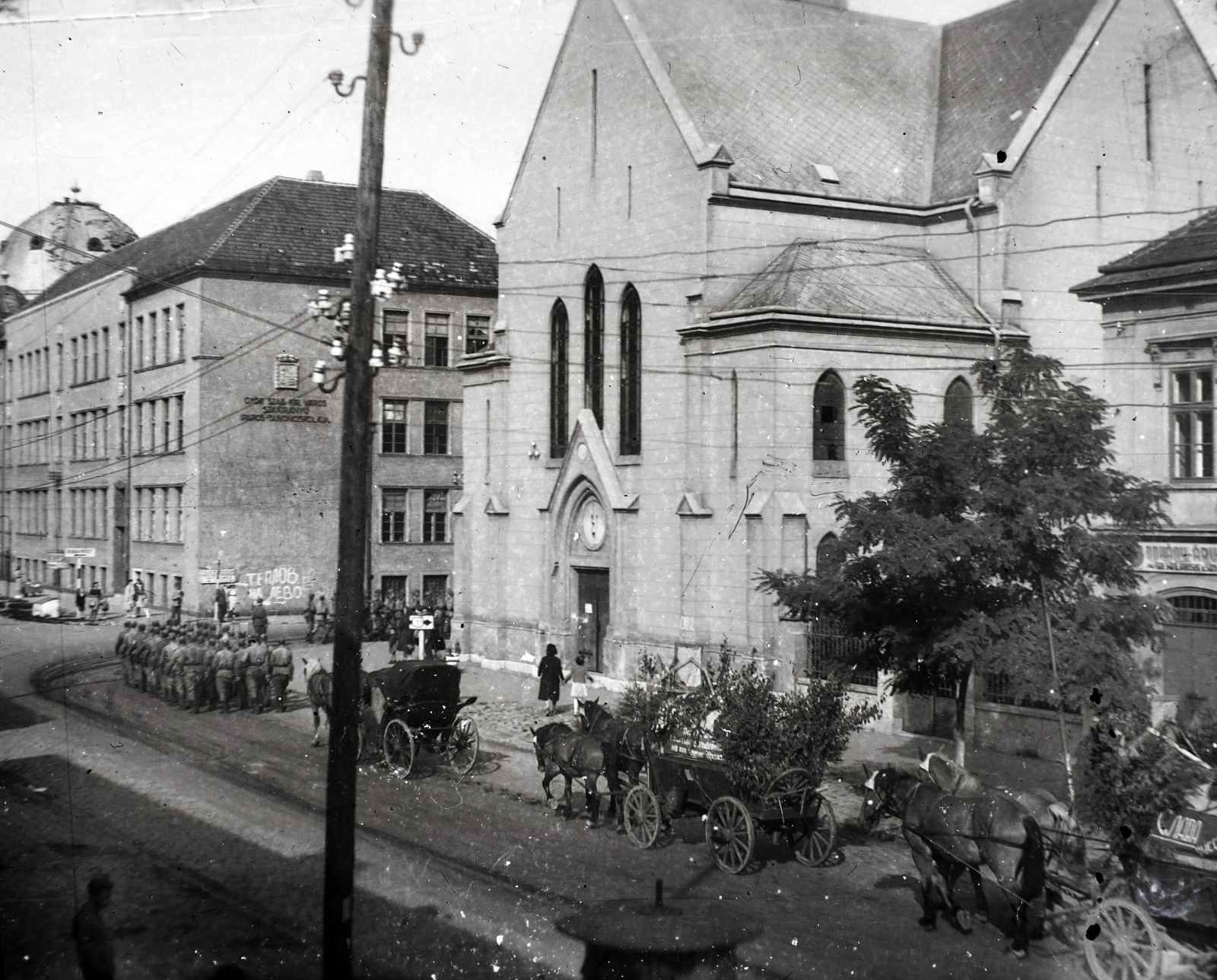 Hungary, Győr, Kossuth Lajos utca a Petőfi térnél, előtérben a református templom, balra az egykori Iparostanonc-iskola (később a Győri SZC Kossuth Lajos Középiskolája és Kollégiuma), háttérben a Zsinagóga a Dr. Róth Emil (Erkel Ferenc) utcánál., 1945, Tóth Árpád, church, pylon, Horse-drawn carriage, pylon, graffiti, military, Fortepan #203255