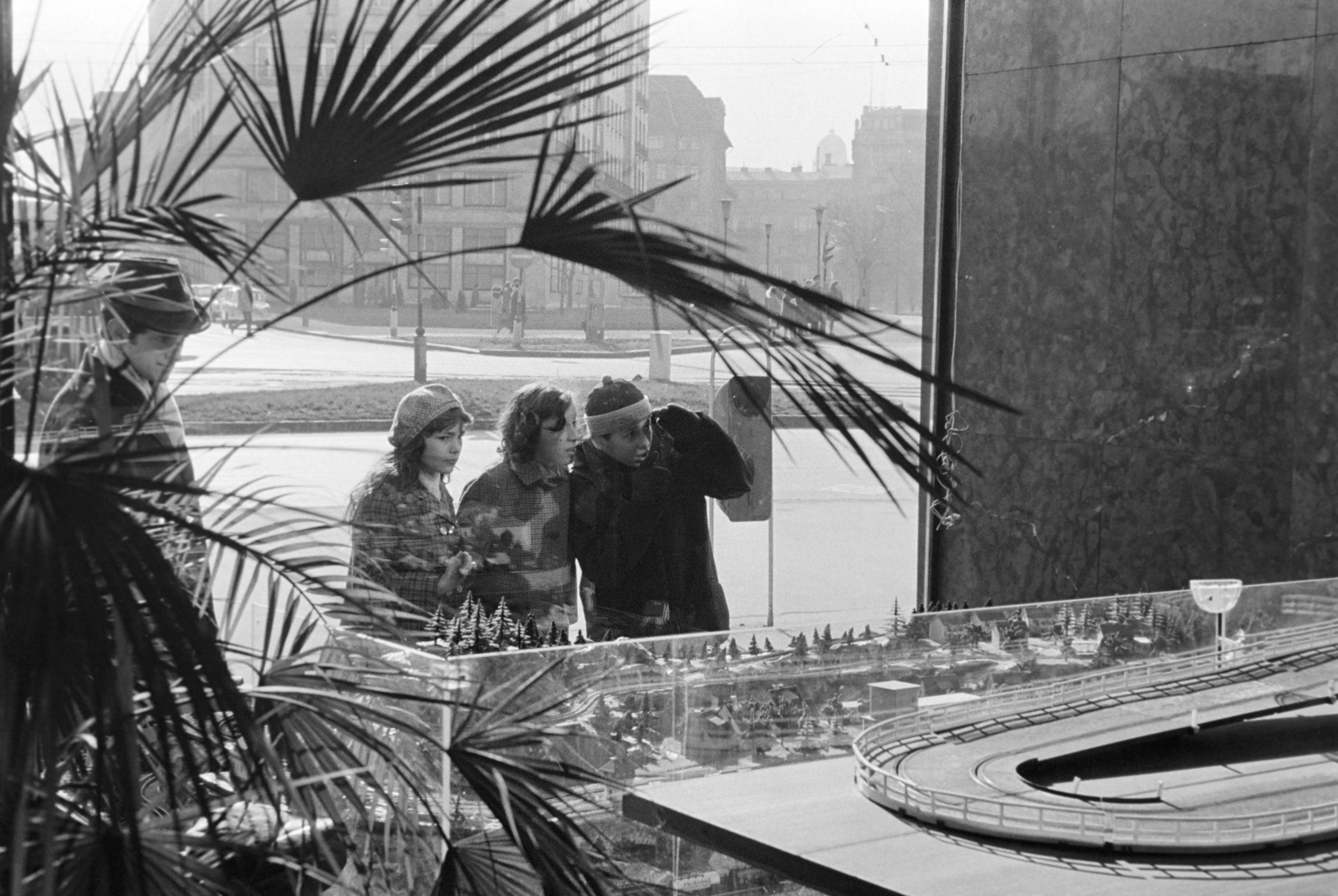 Magyarország, Budapest VI., Deák Ferenc tér 6., Anker-ház, kilátás a Hobby bolt kirakatán keresztül, szemben a Budapesti Rendőr-főkapitányság épülete (később szálloda)., 1970, Kereki Sándor, Budapest, gyerekek, kíváncsiság, dísznövény, Fortepan #204997