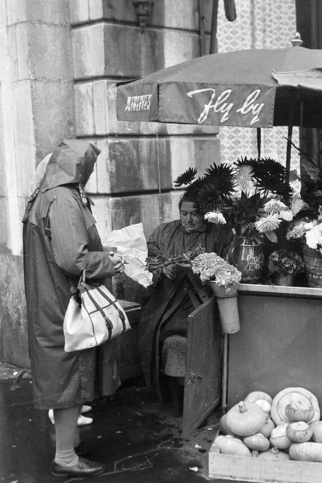 Magyarország, Budapest V., Vörösmarty tér, virágárus a Gerbeaud (Vörösmarty) cukrászda terasza mellett a Dorottya utca felőli oldalon., 1969, Kereki Sándor, virágárus, Budapest, táska, esőkabát, Fortepan #205046