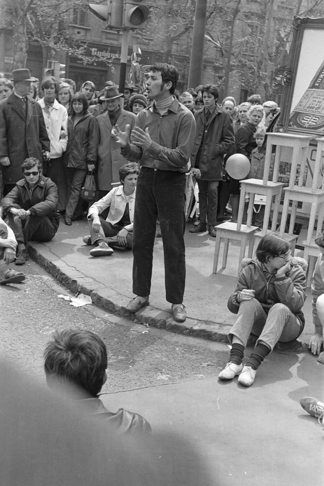 Hungary, Budapest VI., Andrássy út (Népköztársaság útja) - Bajza utca kereszteződés. Performansz a május 1-i felvonulás résztvevőinek., 1970, Kereki Sándor, Budapest, sitting on the ground, youth, audience, play, Fortepan #206217