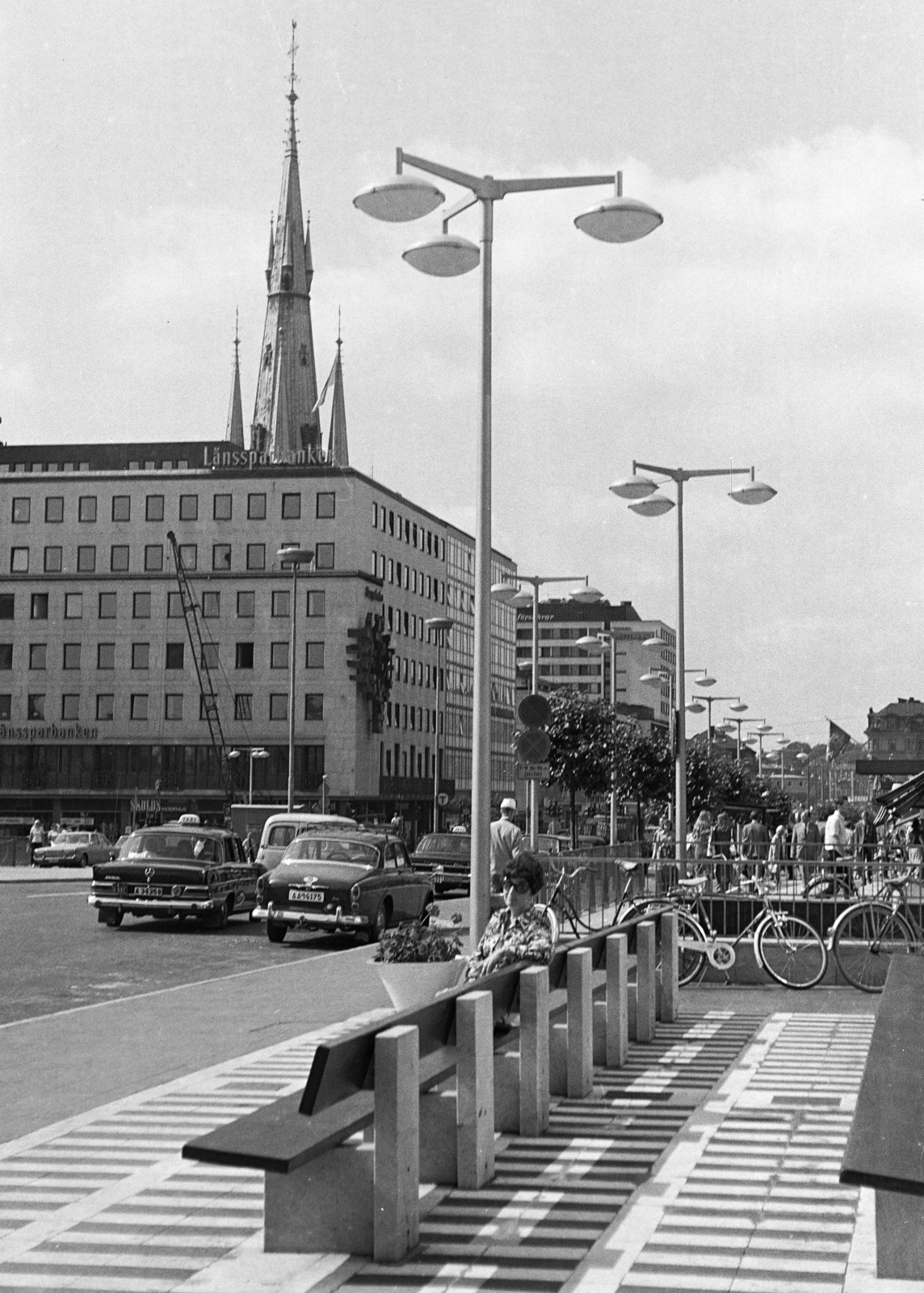 Svédország, Stockholm, Sergels Torg. Háttérben a Klarabergsgatan 23-as számú épület és a Szent Klára-templom (Sankta Klara kyrka) tornya., 1970, Kopányi György, kerékpár, pihenőhely, utcai lámpa, Fortepan #206378
