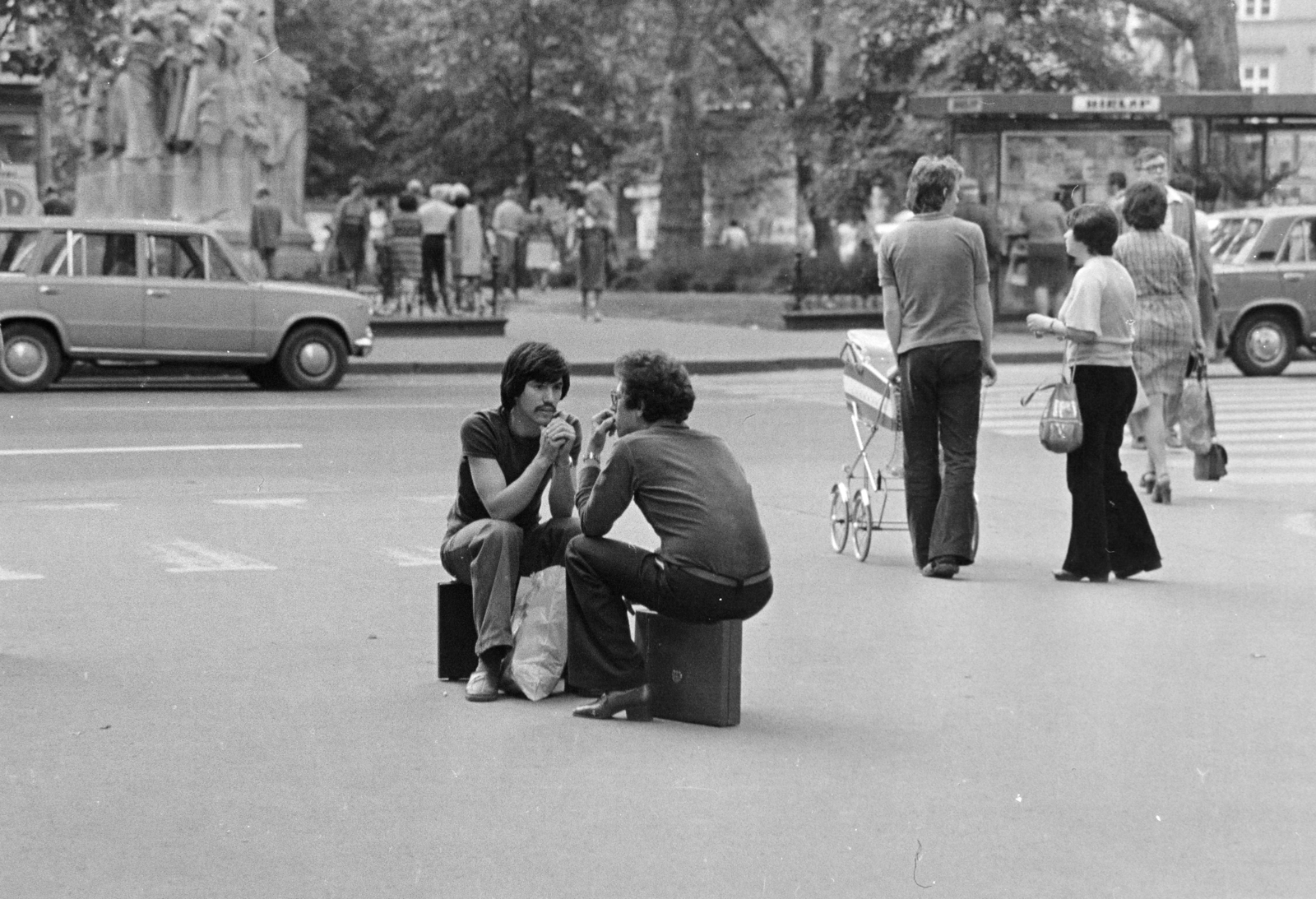 Magyarország, Budapest V., Vörösmarty tér, balra Vörösmarty Mihály szobrának talapzata látszik., 1980, Kereki Sándor, Budapest, Best of, életkép, ül, diplomatatáska, beszélgetés, férfiak, fiatalság, Fortepan #206475