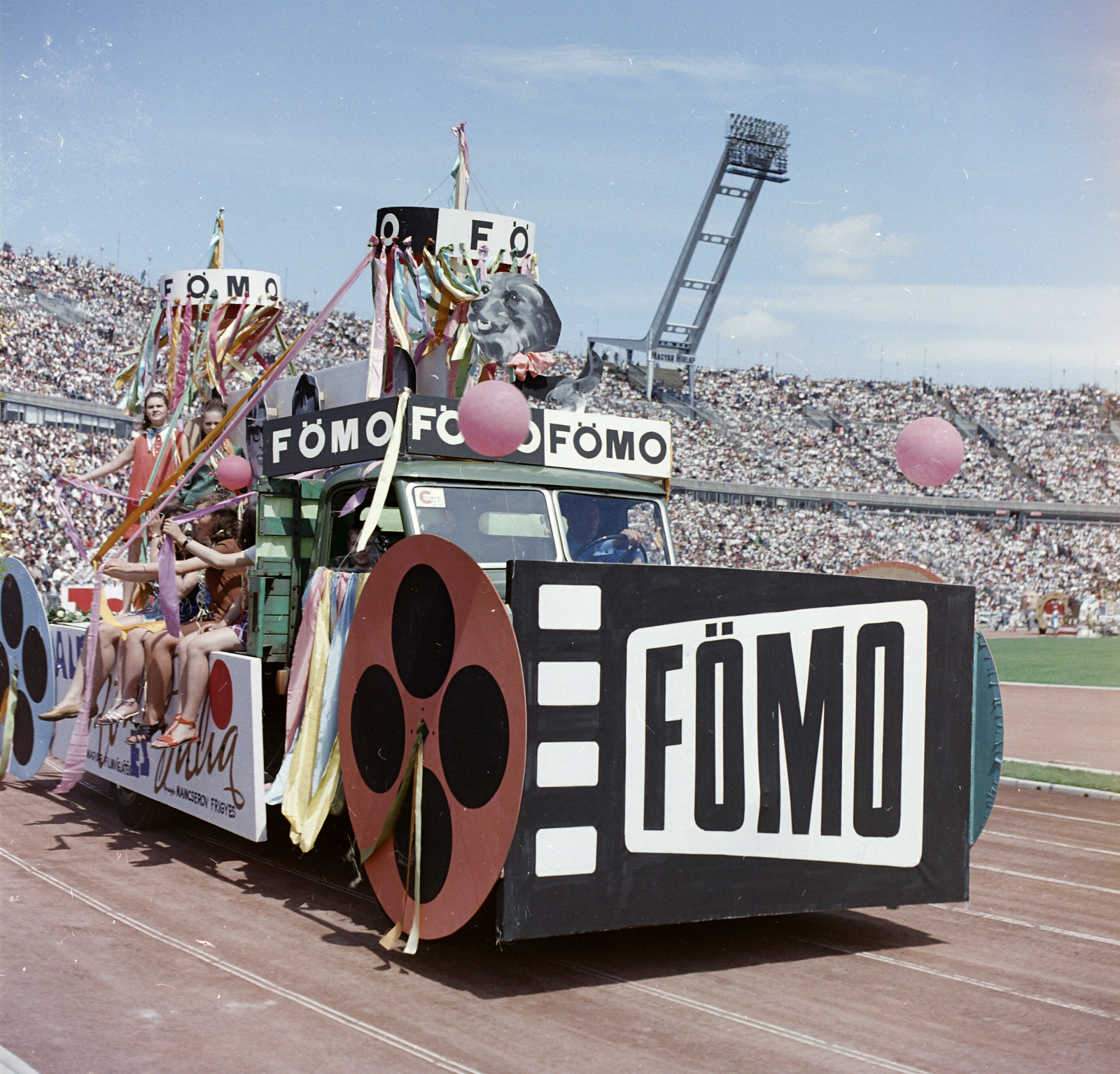 Magyarország, Népstadion, Budapest XIV., a Fővárosi Moziüzemi Vállalat (FŐMO) által forgalmazott film plakátja a Színészek-Újságírók Rangadó (SZÚR) alkalmával felvonuló teherautón., 1969, FŐFOTÓ, Budapest, Fortepan #208455