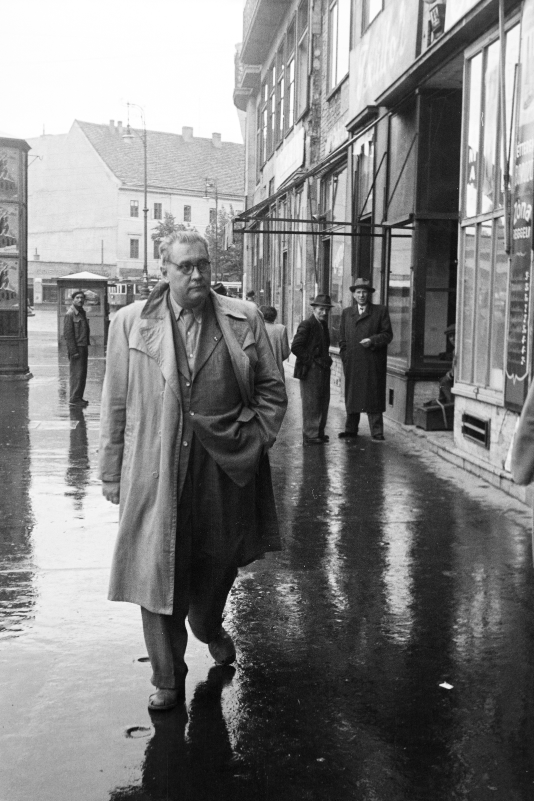 Hungary, Budapest VII., Tiszay Andor író. A felvétel a Károly (Tanács) körút 23., a Megálló Étterem előtt készült., 1954, Aradi Péter, Szenczi Mária, Budapest, rain, pavement, hands in pockets, glasses, trench coat, writer, Fortepan #212132