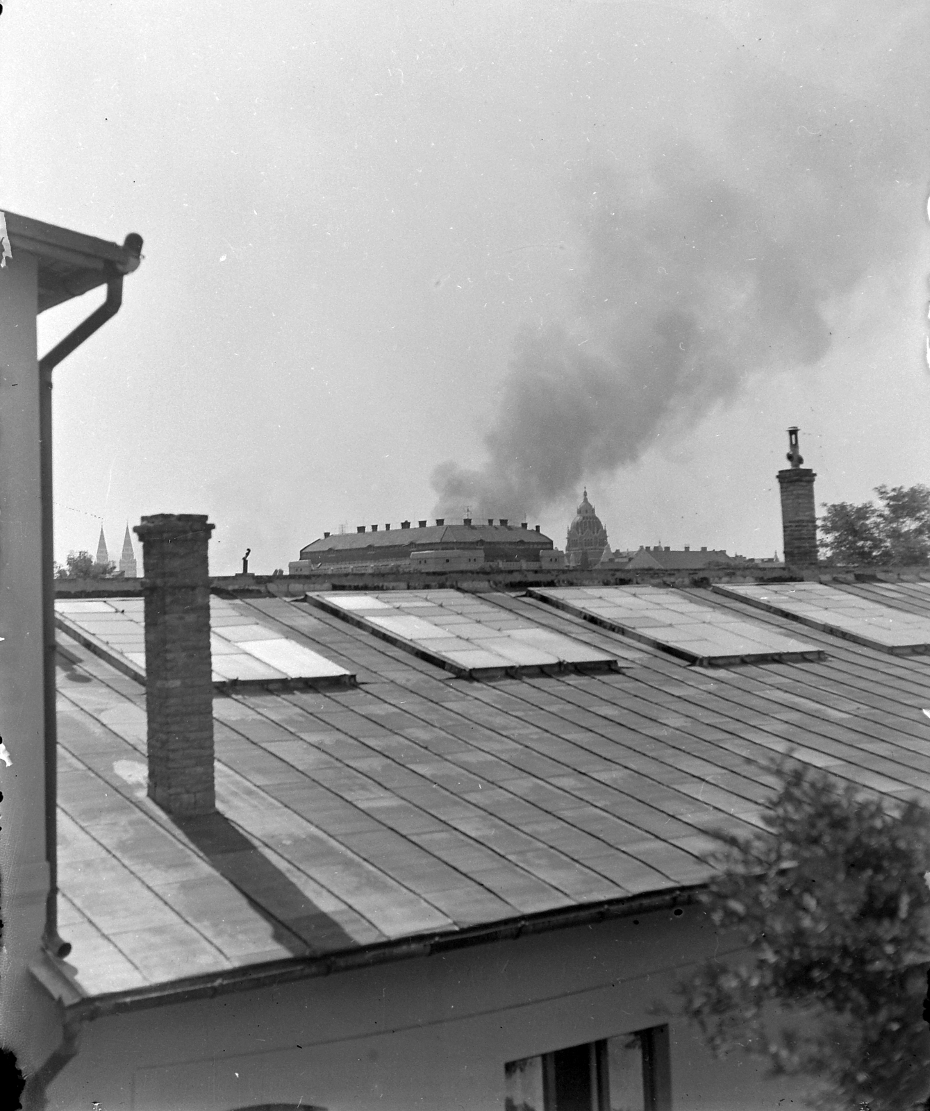 Magyarország, Szeged, Kossuth Lajos sugárút 40., a távolban balra a Fogadalmi templom tornyai, jobbra a Zsinagóga kupolája., 1944, Fortepan, bombázás, háztető, kémény, ereszcsatorna, füstfelhő, Fortepan #21265