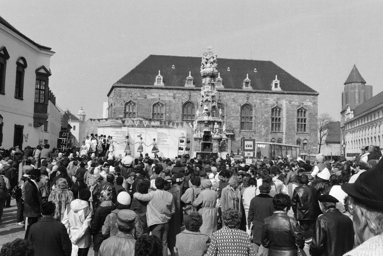 Hungary, Budapest I., Szentháromság tér, néptáncegyüttes bemutatója. Balra a Tárnok utca - Szentháromság utca sarkán a régi budai városháza. Szemben a Szentháromság-szobor mögött az egykori Pénzügyminisztérium épülete. Jobbra a Hilton szálló a Szent Miklós-templom tornyával., 1987, Szalay Zoltán, Budapest, Fortepan #213131