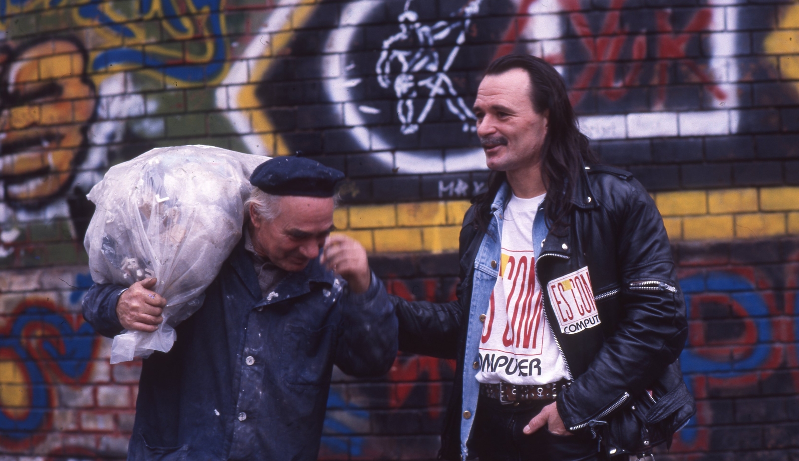 Magyarország, Budapest VIII., Golgota út, a felvétel a Vörösmarty Művelődési Ház előtt készült, jobbra a Fekete Lyuk alternatív klubba érkező Nagy Feró a Beatrice együttes tagja. A felvétel 1991-ben készült., 1990, Urbán Tamás, Budapest, színes, híres ember, vállon vinni, zsák, Fortepan #213834