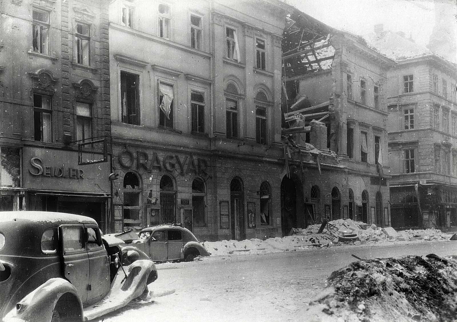 Magyarország, Budapest V., Kossuth Lajos utca, a kép jobb szélén a Szép utca torkolata., 1945, Vörös Hadsereg, Budapest, épületkár, hó, üzletportál, automobil, függöny, Fortepan #217777