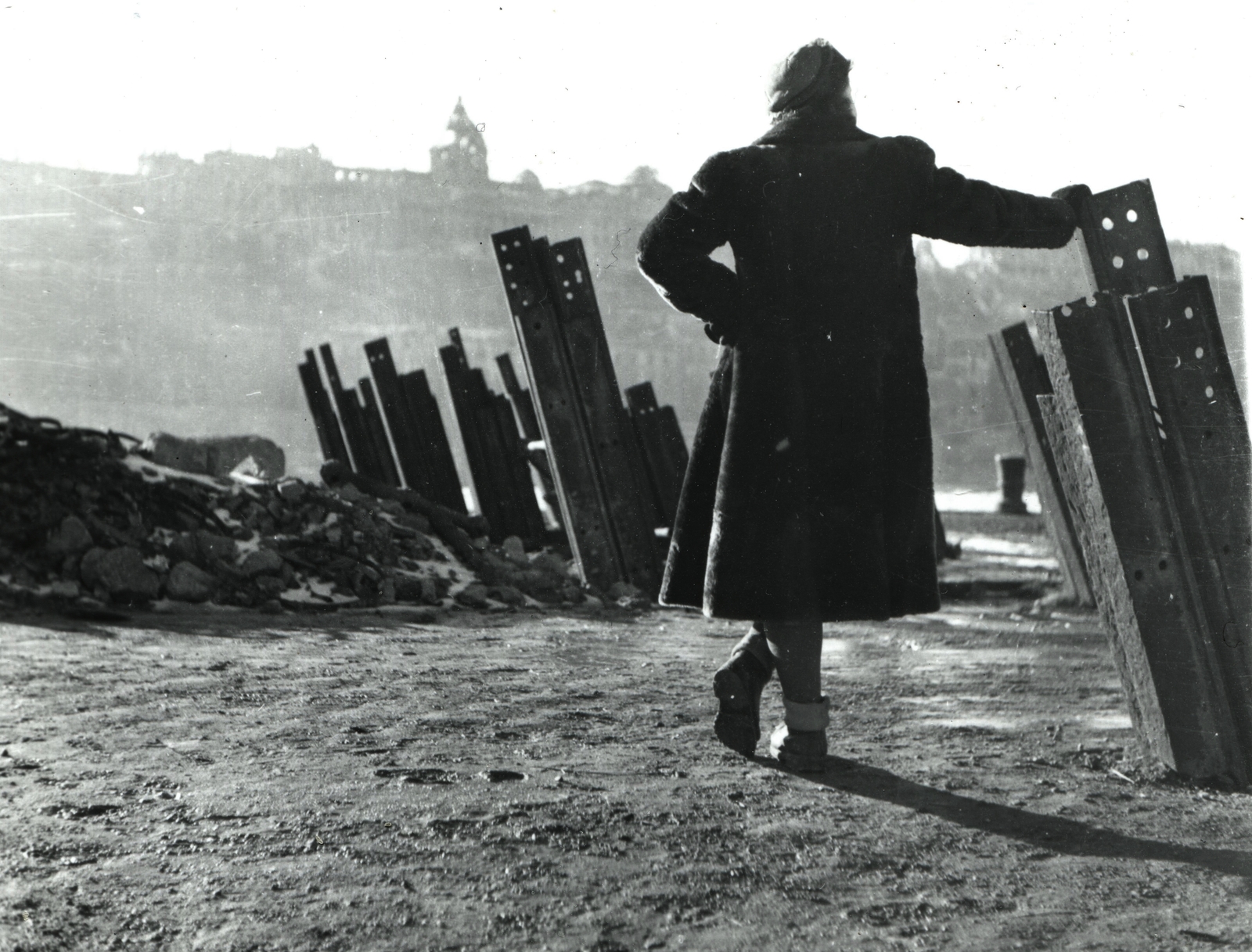 Hungary, Budapest V.,Budapest I., harckocsi akadály a pesti alsó rakparton a Vigadó tér közelében. Háttérben a Királyi Palota (később Budavári Palota)., 1945, Mihályi Balázs, anti-tank obstacles, Budapest, coat, woman, back, leaning, Fortepan #217833