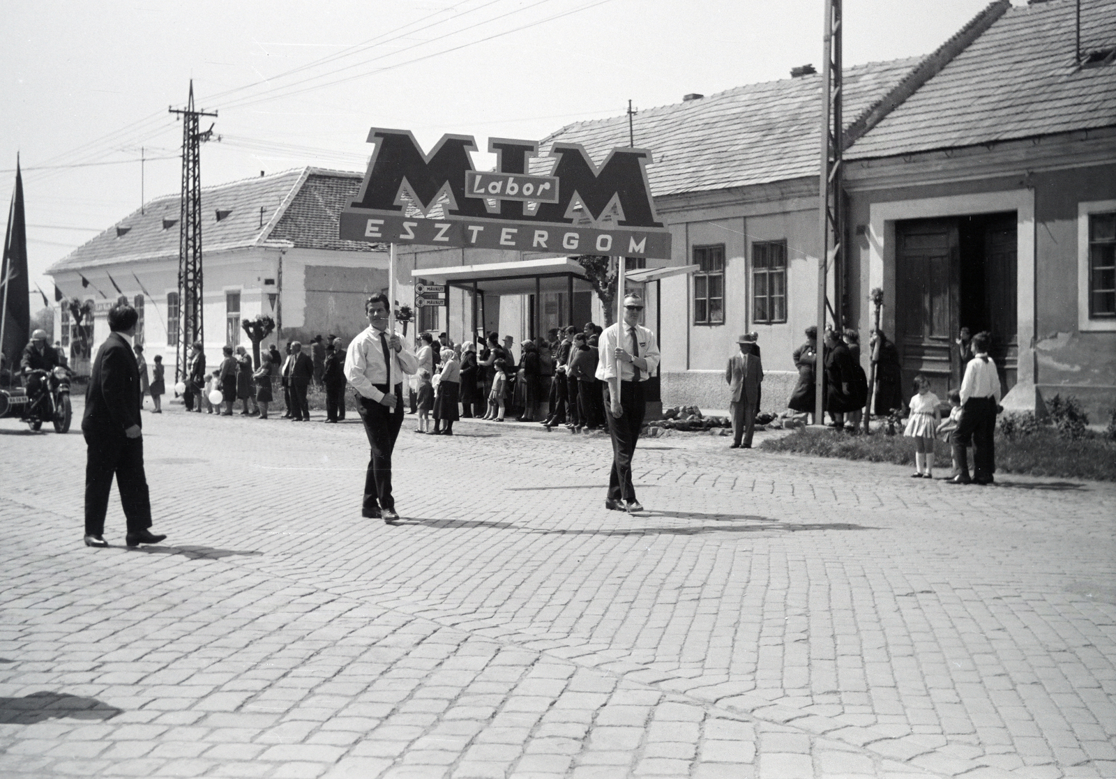 Magyarország, Esztergom, Kossuth Lajos utca (11-es főút), május 1-i felvonulás. Háttérben az autóbusz-megálló mögött a 73-as számú ház., 1974, Almássy László, transzparens, Fortepan #217960