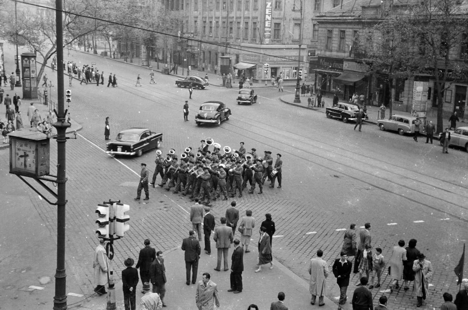 Hungary, Budapest V.,Budapest VI., Bajcsy-Zsilinszky út az Andrássy út (Magyar Ifjúság útja) saroktól a Deák Ferenc tér felé nézve. Május 1-i felvonuláson és nagygyűlésen résztvevő munkásőrök., 1957, BL, Budapest, automobile, public clock, crosswalk, signal, safety island, tram stop, greengrocer, furrier, watch jewelry store, perfume store, directing traffic, wind band, Workers' Militia, Fortepan #218186