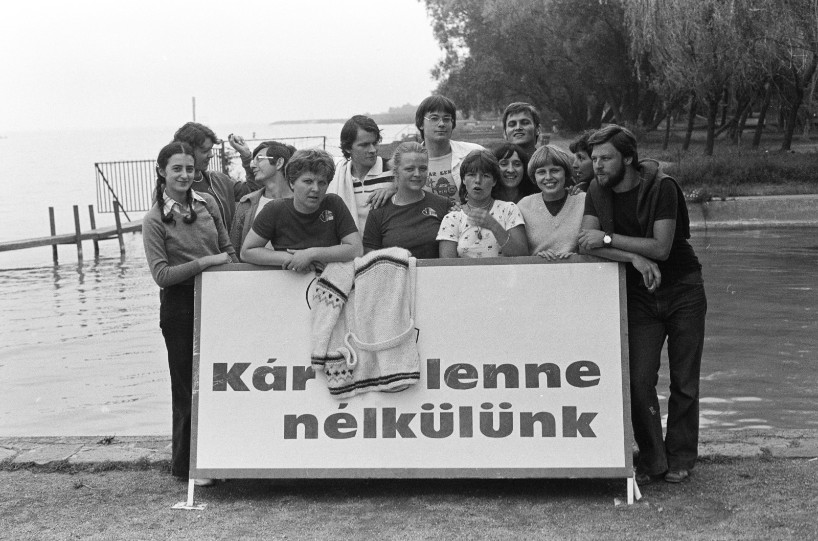 Magyarország,Balaton, Fonyód, park a kikötőnél, háttérben a strand., 1982, Krizsanóczi Anna, tó, csoportkép, felirat, tábla, fiatalság, part, biztosító, Fortepan #219382