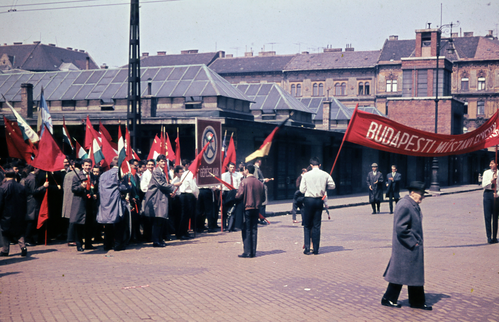 Hungary, Budapest VII., Garay tér a Cserhát utca - Alpár utca saroknál, május 1-i felvonuláson résztvevő Budapesti Műszaki Egyetem Gépész kari hallgatók csoportja., 1965, N. Kósa Judit, market, march, Budapest, colorful, flag, winter coat, banner, 1st of May parade, Fortepan #220006