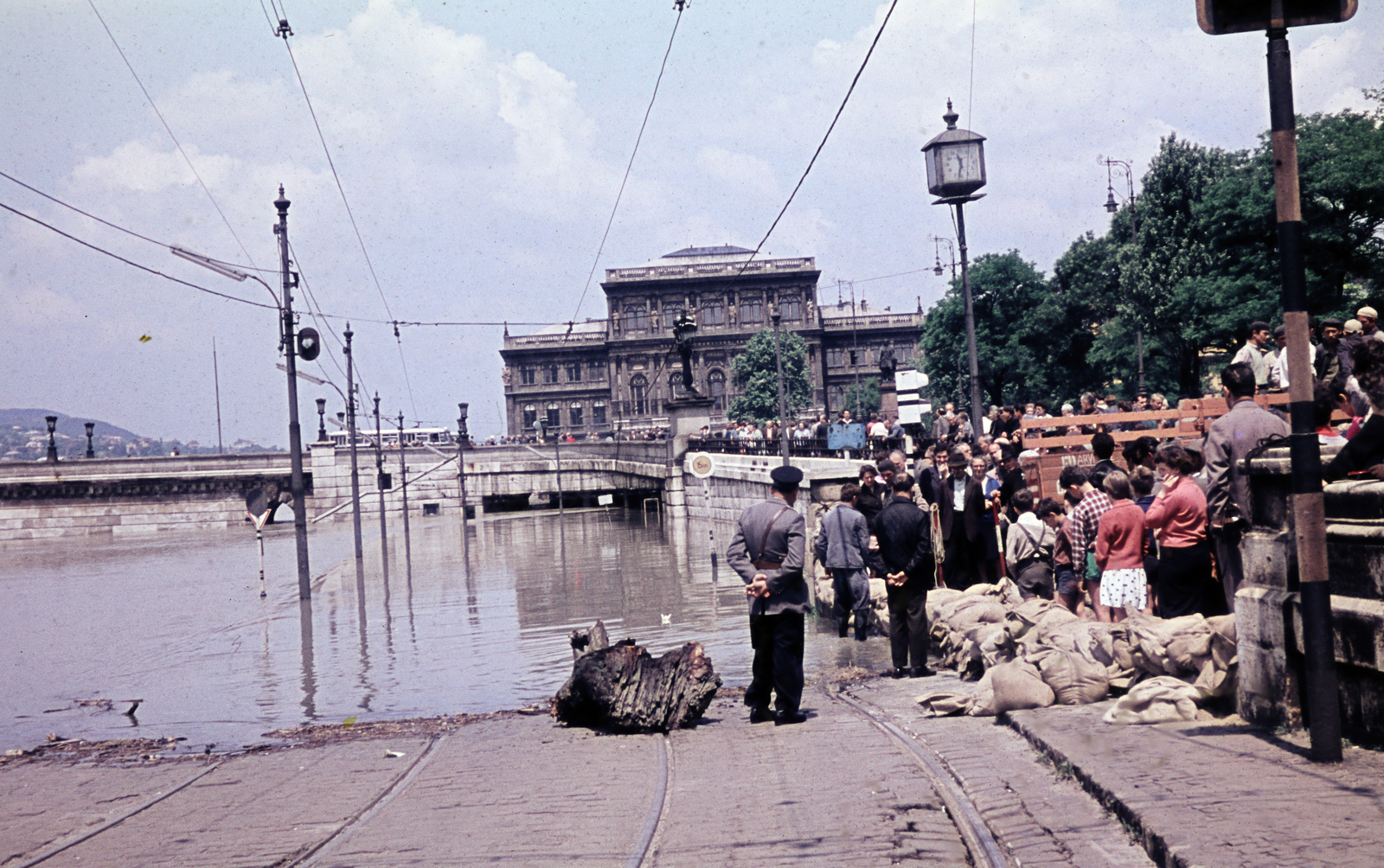Magyarország, Budapest V., pesti alsó rakpart a a Széchenyi István (Roosevelt) térnél árvíz idején. Háttérben a Magyar Tudományos Akadémia székháza., 1965, N. Kósa Judit, színes, árvíz, Budapest, rendőr, bámészkodás, óra, homokzsák, Fortepan #220015