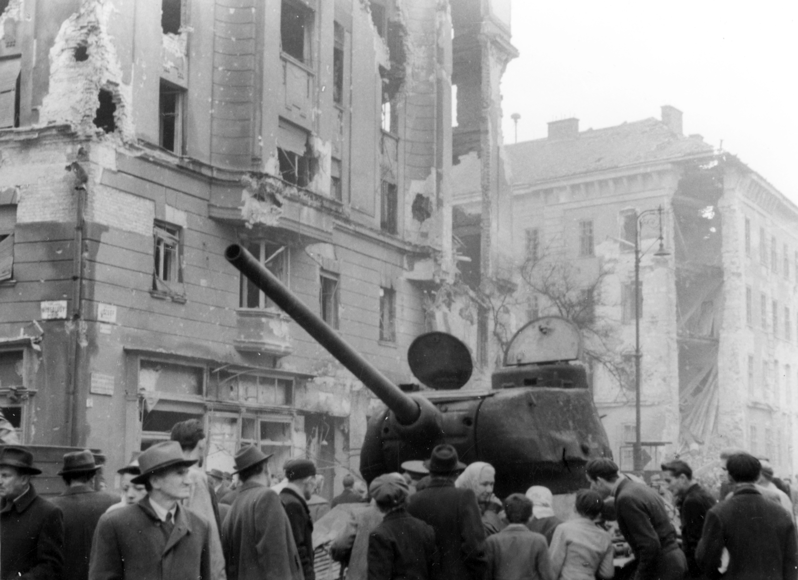 Hungary, Budapest VIII., József körút - Corvin (Kisfaludy) köz sarok, kiégett szovjet T-34/85 harckocsi. Háttérben az Üllői útnál a Kilián laktanya romos épülete., 1956, Darányi Sándor, Budapest, damaged building, wreck, curiosity, street name sign, Fortepan #221612