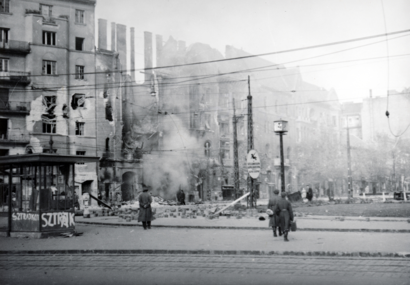 Hungary, Budapest XI., Móricz Zsigmond körtér, háttérben a megrongálódott 2-es számú ház, jobbra a Bartók Béla út., 1956, Matthaeidesz Konrád, Budapest, revolution, damaged building, public clock, label, Fortepan #221638