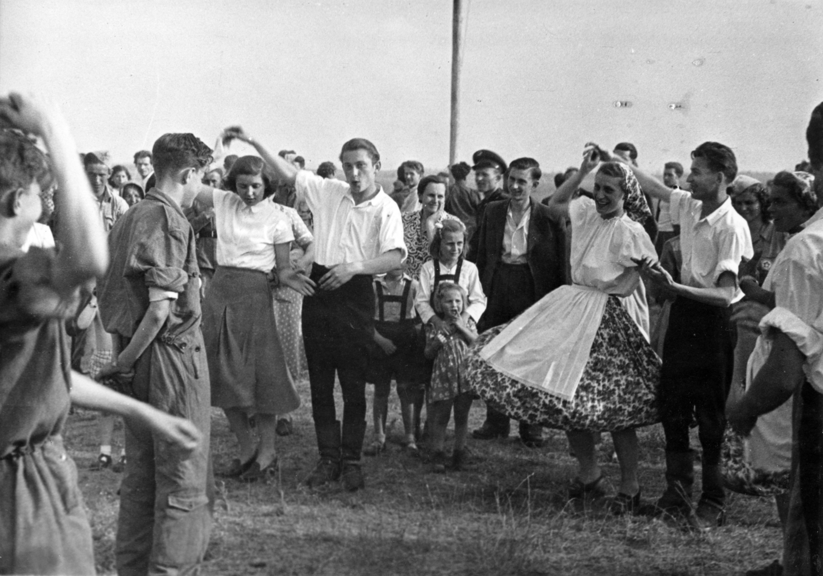 Hungary, Mátyásföld Airport, Budapest XVI., repülőnövendékek táncolnak a DISZ (a Dolgozó Ifjúság Szövetsége) egy éves fenállásának tiszteletére rendezett repülőbemutató alkalmával, 1951. június 17-én., 1951, Nasztanovics Ferenc, folk dance, folk costume, dance, Budapest, audience, festive, Fortepan #222057