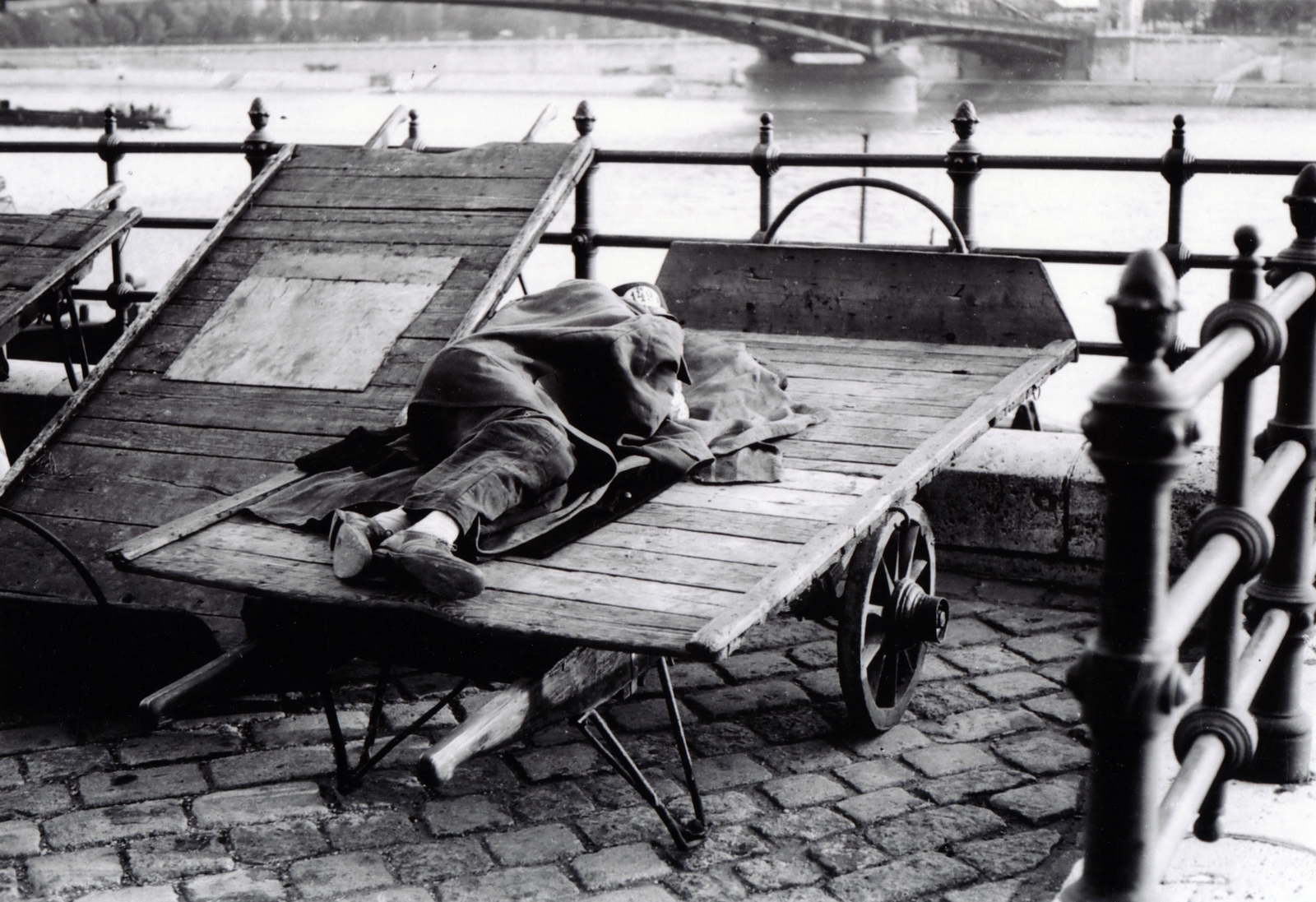 Hungary, Budapest V., a felvétel a pesti alsó rakparton készült, a pihenő, munkára váró hordár mögött a Szabadság (Ferenc József) híd., 1940, Fortepan/Album064, handbarrow, solitude, poverty, sleeping, Budapest, Fortepan #223232