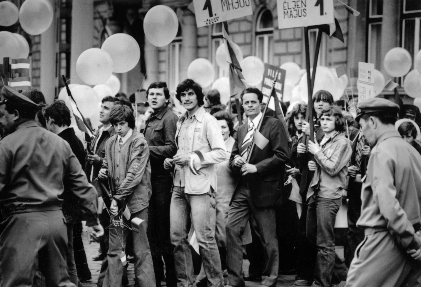 Magyarország, Budapest VII., május 1-i felvonulás résztvevő érkeznek a Dembinszky utcából a Dózsa György útra, háttérben a 68-as számú ház., 1974, Középületépítő Vállalat - Kreszán Albert - Koczka András - Kemecsei József, Budapest, Fortepan #227134