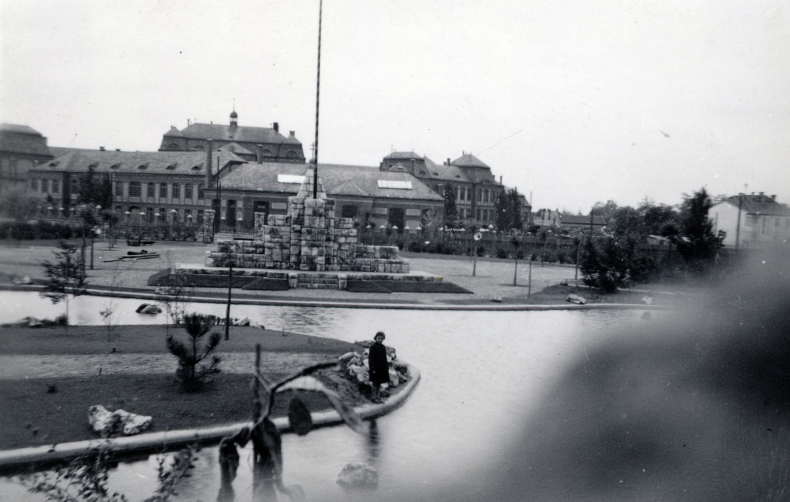 Magyarország, Budapest IV., Hősök ligete (a mai Házy Erzsébet sétány környéke), középen az Országzászló. Háttérben a M. kir. állami fa- és fémipari szakiskola (később Újpesti Két Tanítási Nyelvű Műszaki Szakgimnázium és Szakközépiskola)., 1935, Vízkelety László, Budapest, Fortepan #227670