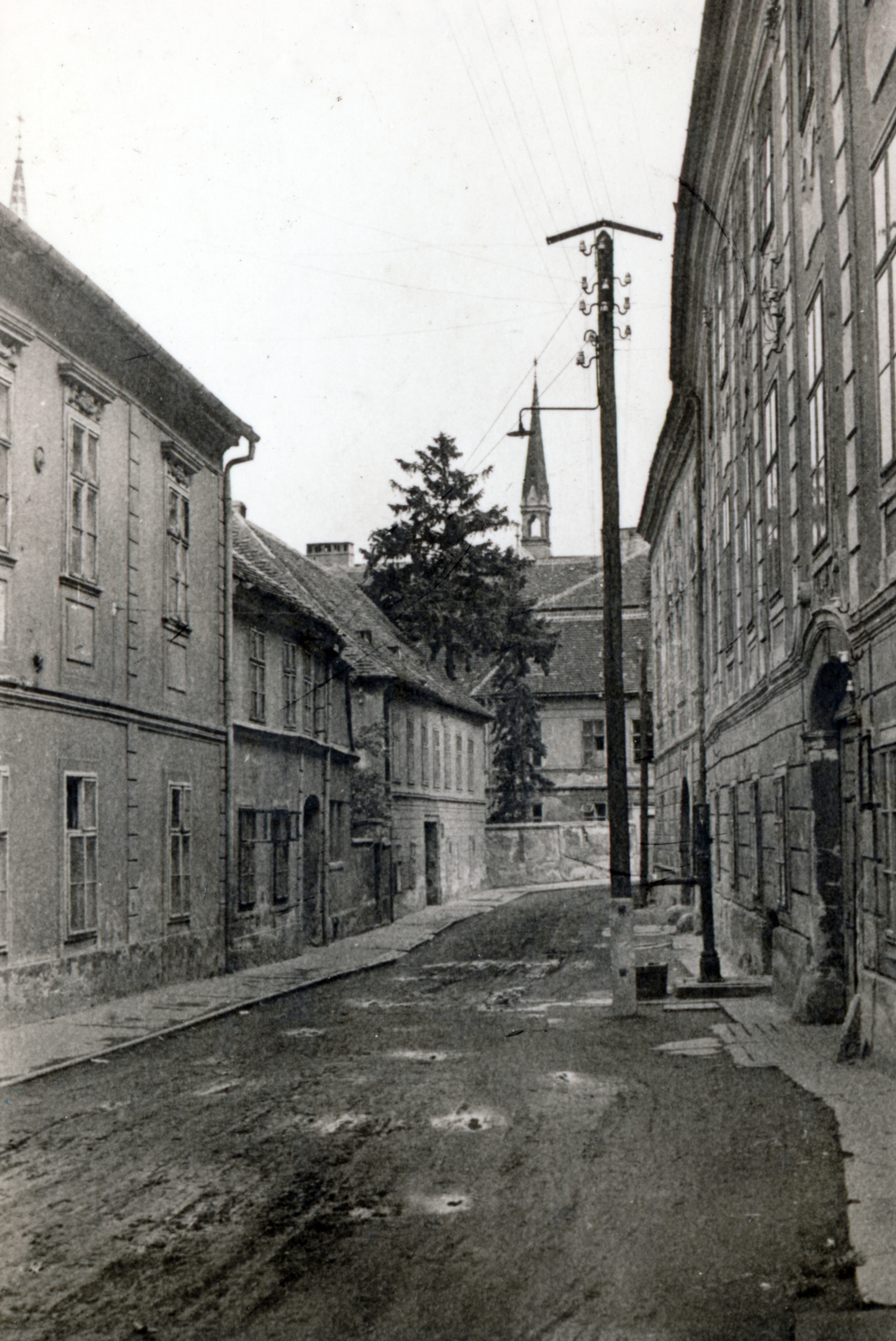 Magyarország, Kőszeg, Chernel utca, háttérben a Jézus szíve plébániatemplom huszártornya., 1954, Korner Veronika, sár, utcakép, templomtorony, földút, kút, villanypózna, Fortepan #230078