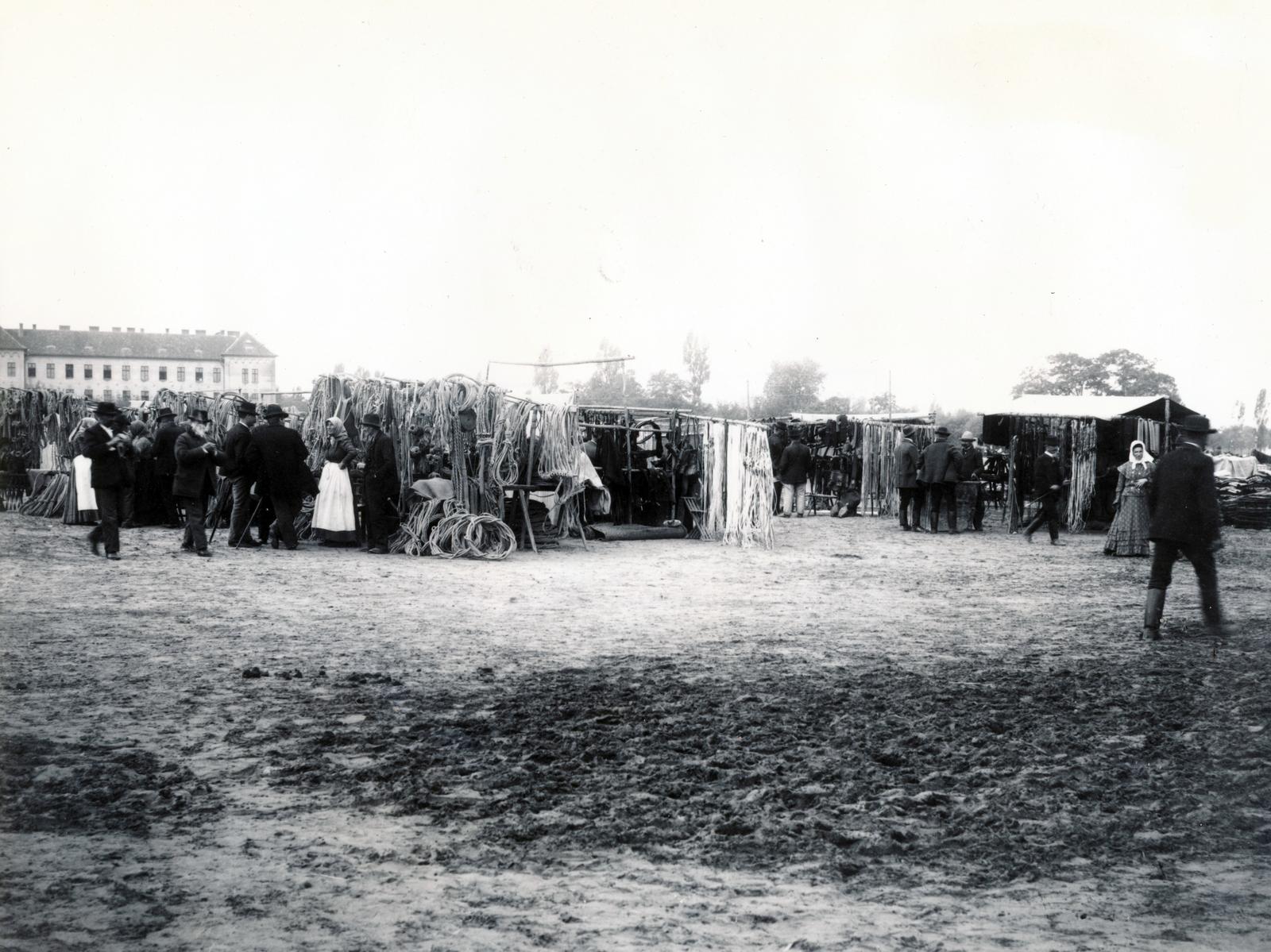 Hungary, Kecskemét, vásártér, balra a háttérben a Ferenc József gyalogsági laktanya (később Zrinyi Miklós laktanya, majd Kodály Zoltán Ének-zenei Általános Iskola)., 1906, Fortepan/Album087, booth, fair, boots, tent, hat, headscarf, folk costume, castle, extinct crafts, Fortepan #230276