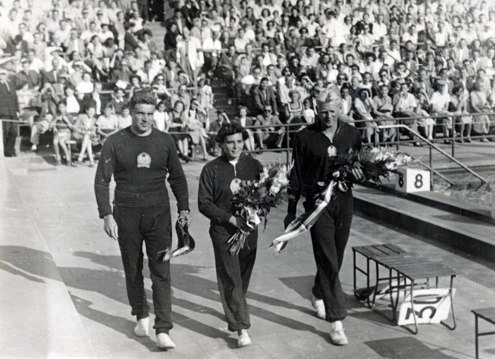 Hungary, Margit Islands, Budapest, Hajós Alfréd Nemzeti Sportuszoda, XII. Főiskolai Világbajnokság. Szívós István vízilabdázó, Székely Éva olimpiai bajnok úszónő, jobbra Tumpek György Európa-bajnok úszó., 1954, Tumpek György, three people, sportsperson, bouquet, swimming pool, spectator, sport jersey, Fortepan #230318