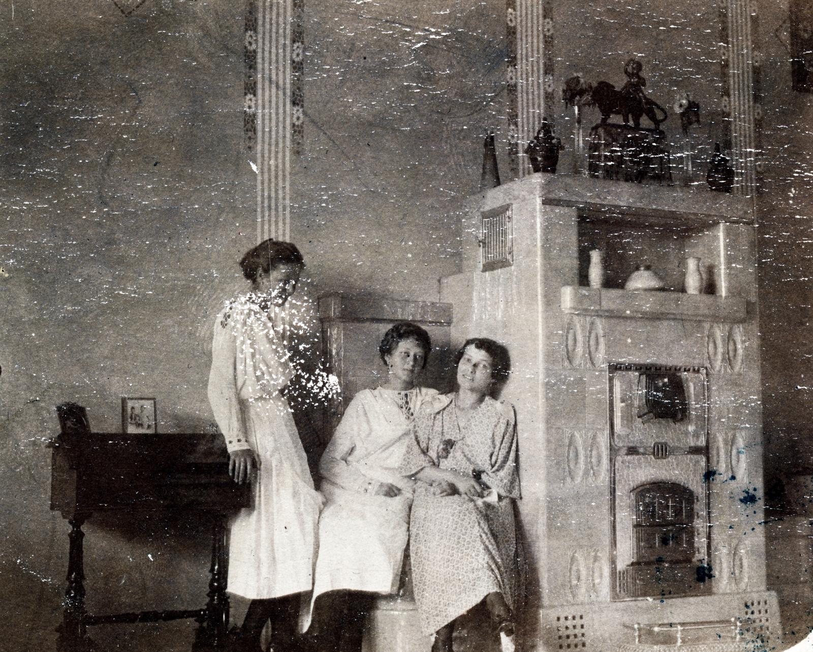 1915, Aczél Frigyes, three people, girls, china, desk, tile stove, damaged photo, stove, Fortepan #232717