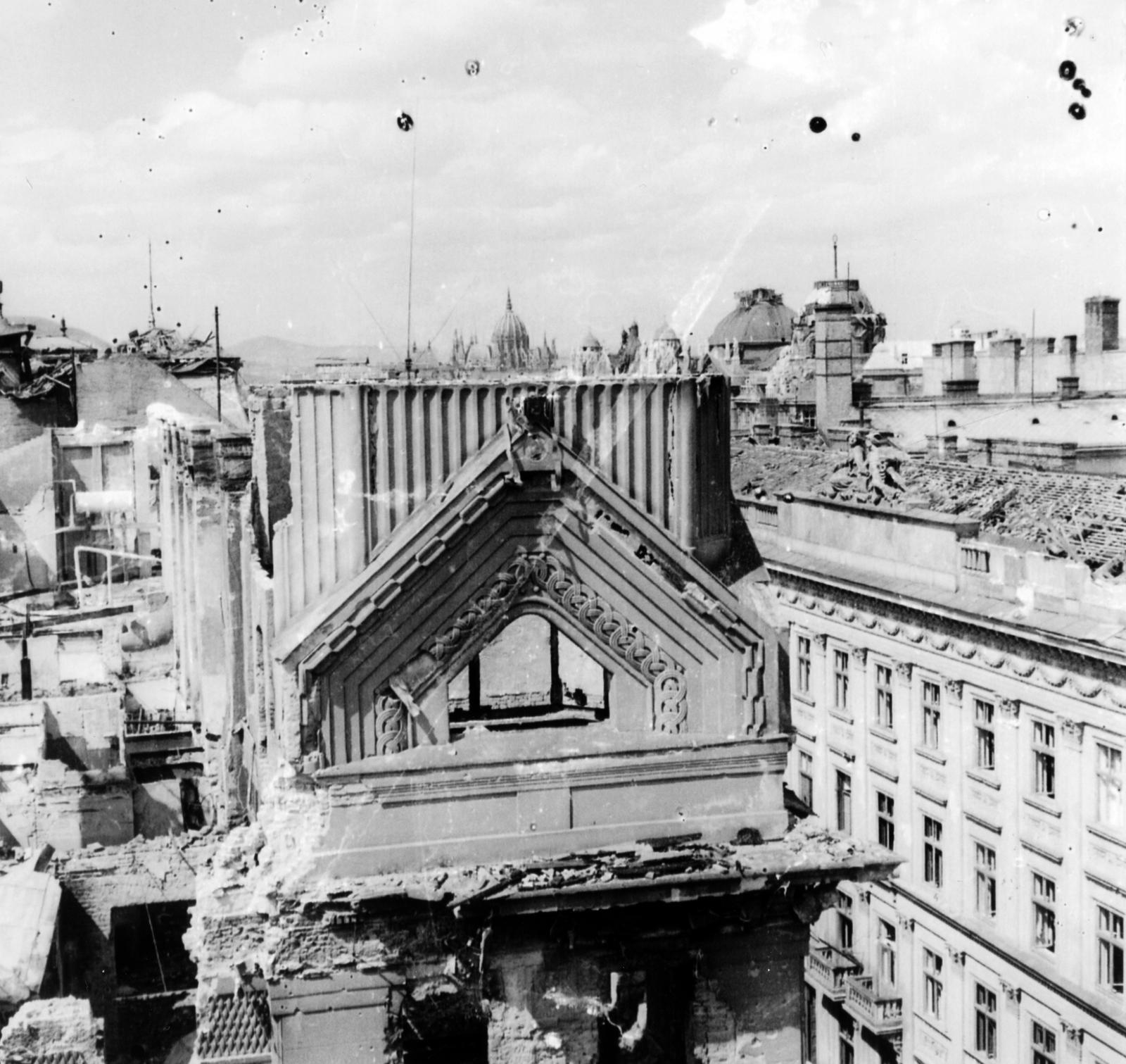 Magyarország, Budapest V., Wekerle Sándor (Wurm) utca - Apáczai Csere János (Mária Valéria) utca sarok, a romos Lloyd-palota mögött a Parlament. Jobb szélen a Wurm-udvar, később Dorottya-palota látható., 1945, Kirilly Gergely, Budapest, háborús kár, Fortepan #235968