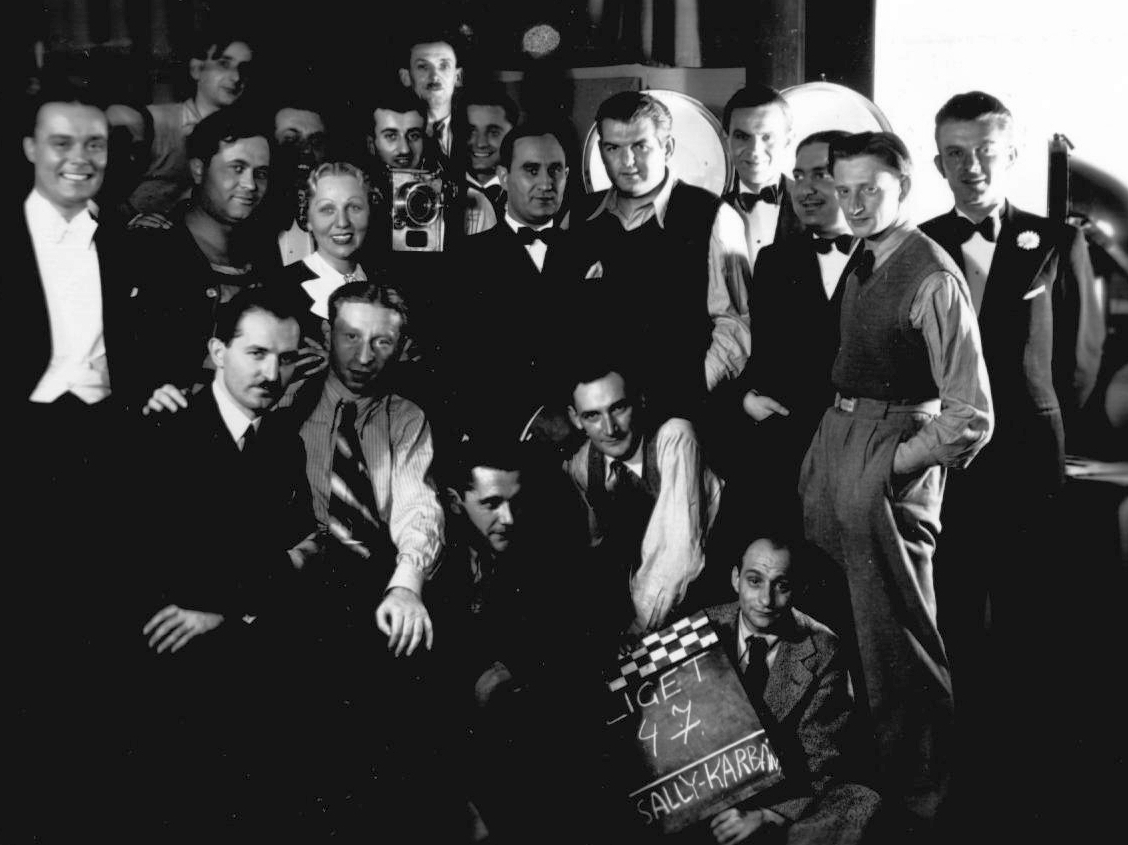 Hungary, A Mindenki muzsikája című hangosfilm-sorozat Ligeti dal című epizódjának forgatásakor készült stábfotó 1936-ból. A képen balról az első Weygand Tibor énekes, mellette jelmezben Fekete Pál tenorista és Sándor Anna énekesnő. A kamera mögött (valószínűleg) Karbán József operatőr, a kamera mellett Kalmár Pál énekes, tőle jobbra Sally Géza zeneszerző és szövegíró. Elől csíkos nyakkendővel Kolozsvári Andor forgatókönyvíró, az epizód rendezője., 1936, Weygand Tibor, filming, celebrity, movie camera, Fortepan #24798