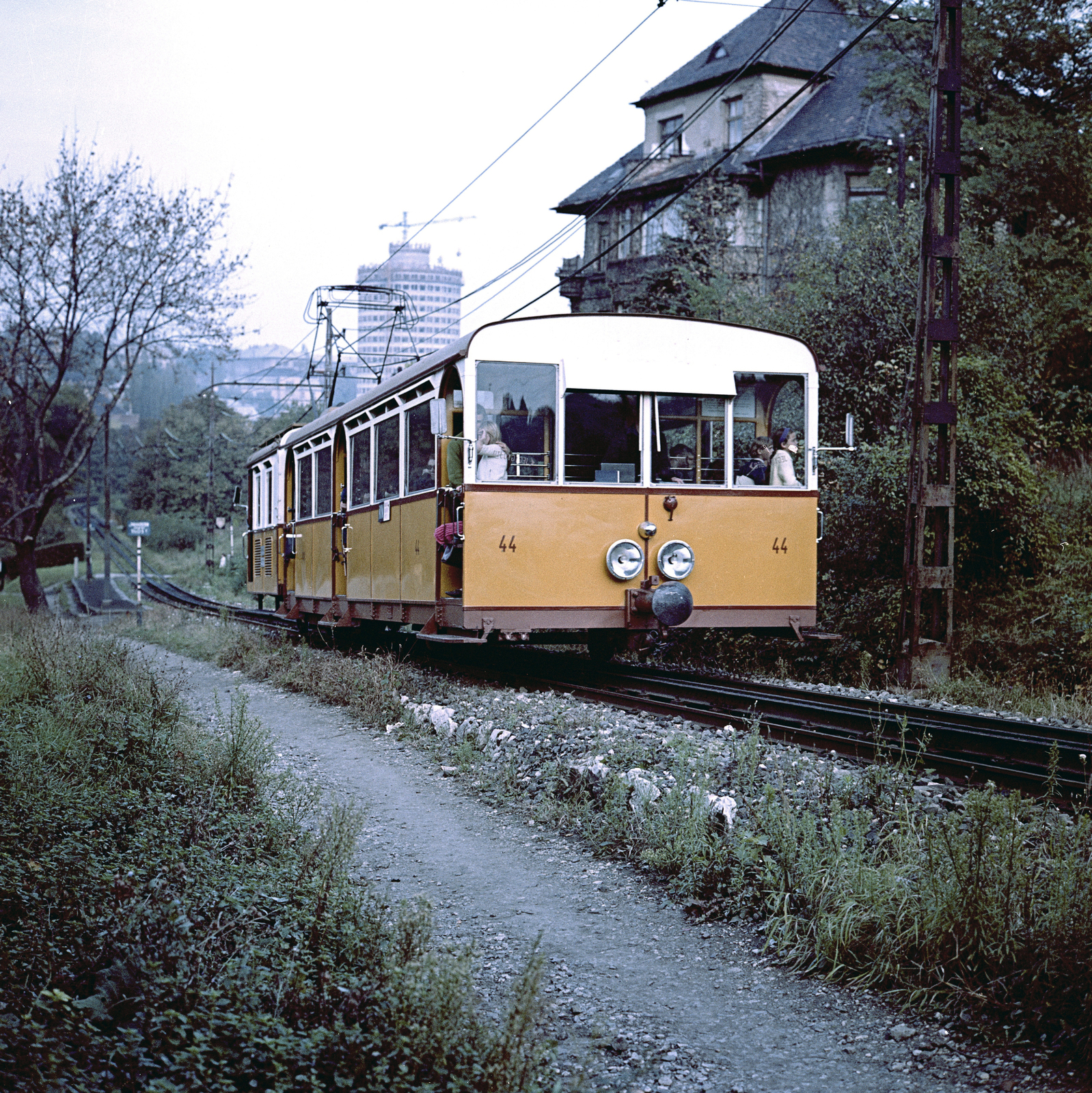 Hungary, Budapest XII., a Fogaskerekű a János Kórház megálló közelében. Háttérben a Budapest körszálló építkezése, jobbra a Fogaskerekű utca mellett álló Pethényi utca 14. számú ház látható., 1966, FŐMTERV, Budapest, funicular train, colorful, Fortepan #252342