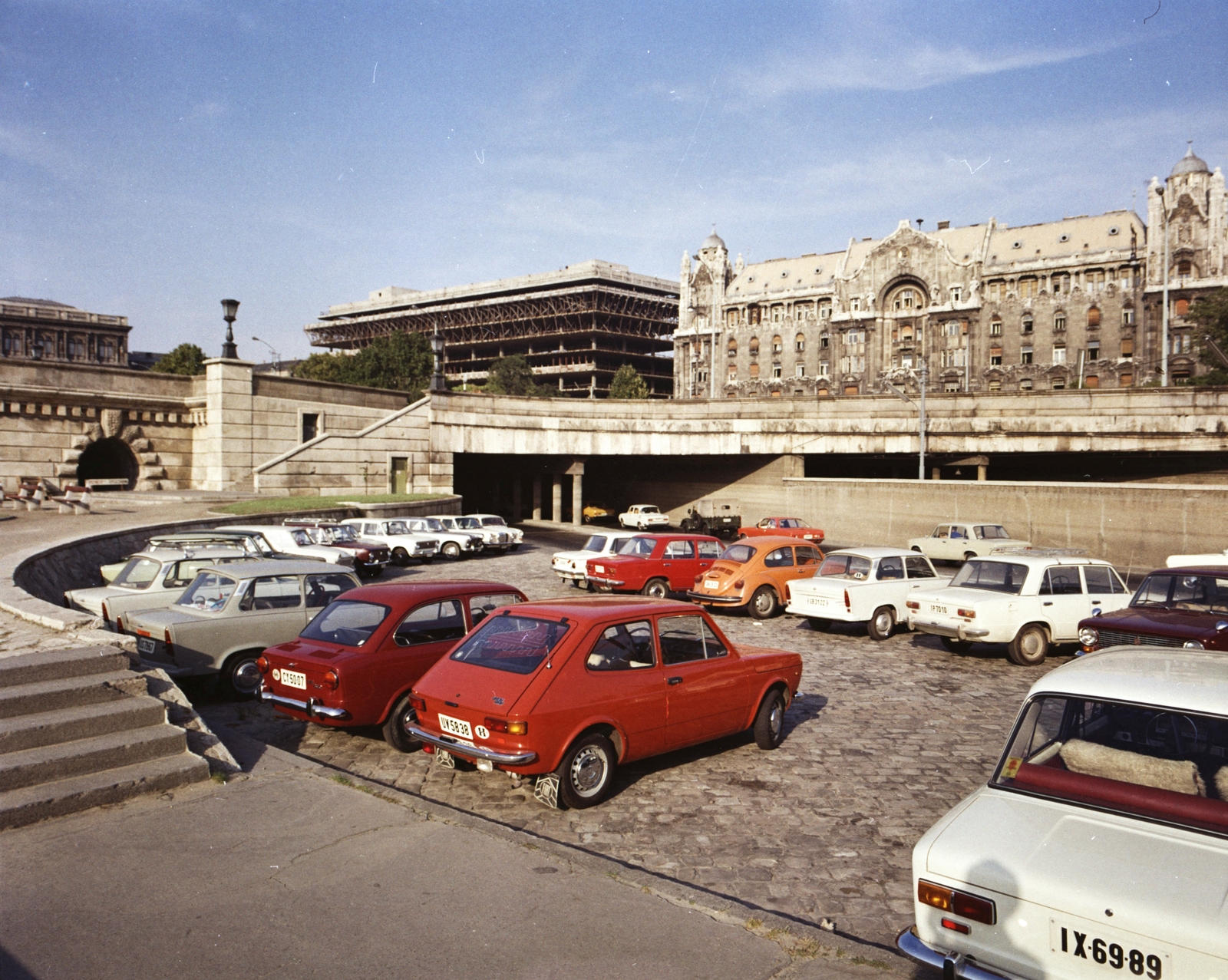 Hungary, Budapest V., pesti alsó rakpart a Széchenyi Lánchíd pesti hídfőjénél. Háttérben a Széchenyi István (Roosevelt) téren a Gresham-palota, ettől balra az állami külkereskedelmi vállalatok székházának tervezett irodaház (Spenótház) építkezése., 1975, FŐMTERV, colorful, Budapest, number plate, Volkswagen Beetle, car park, Fiat-brand, Fortepan #253653
