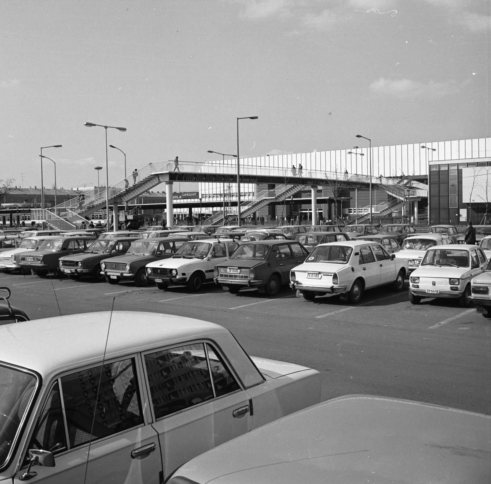 Magyarország, Budapest X.,Budapest XIV., Örs vezér tere, a Kerepesi út feletti gyalogos felüljáró hátterében a Sugár üzletközpont látható., 1982, FŐMTERV, Domonkos Endre, Budapest, parkoló, rendszám, Fortepan #253925