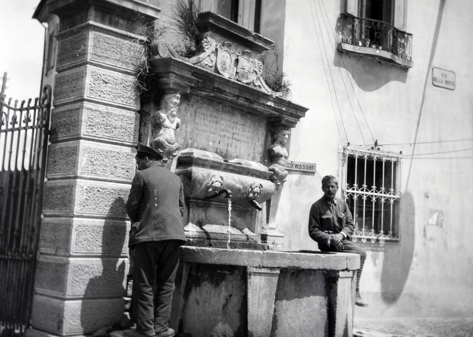 Italy, Belluno, Via Andrea Brustolon, Fontana del Seminario / Fontana della Motta., 1918, Kriszt Béla, soldier, urinate, street name sign, grille, public well, Fortepan #254085